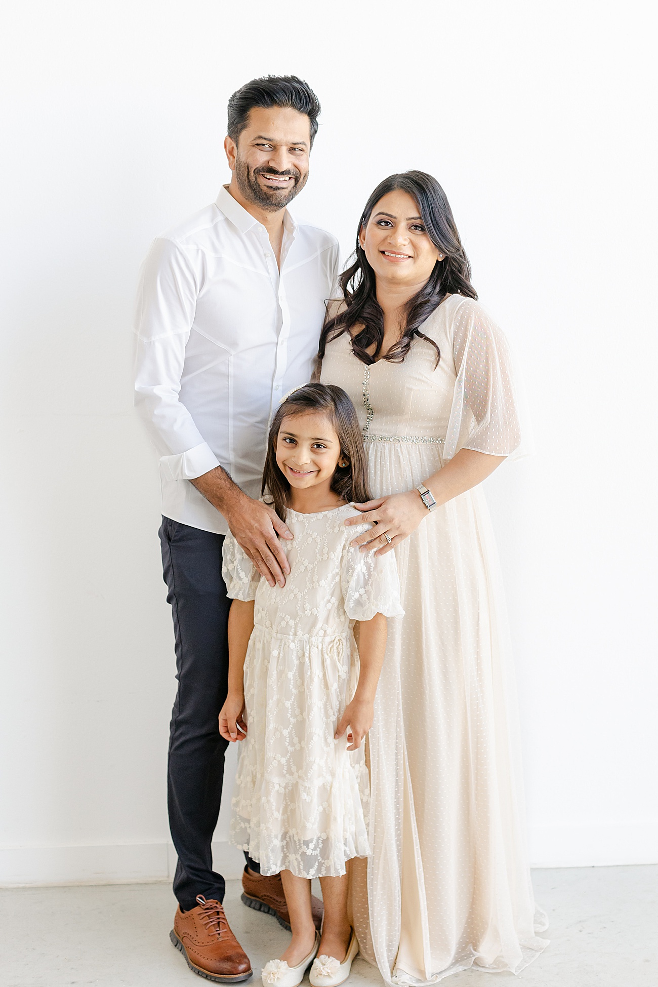 Classic family portrait with everyone smiling at the camera in studio session with Sana Ahmed Photography.