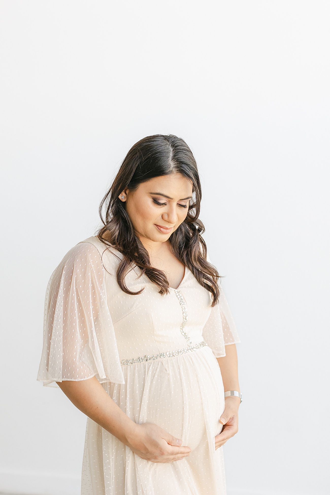 Beautiful expecting Mom wearing off white maxi dress with swiss dots. Photo by Sana Ahmed Photography.