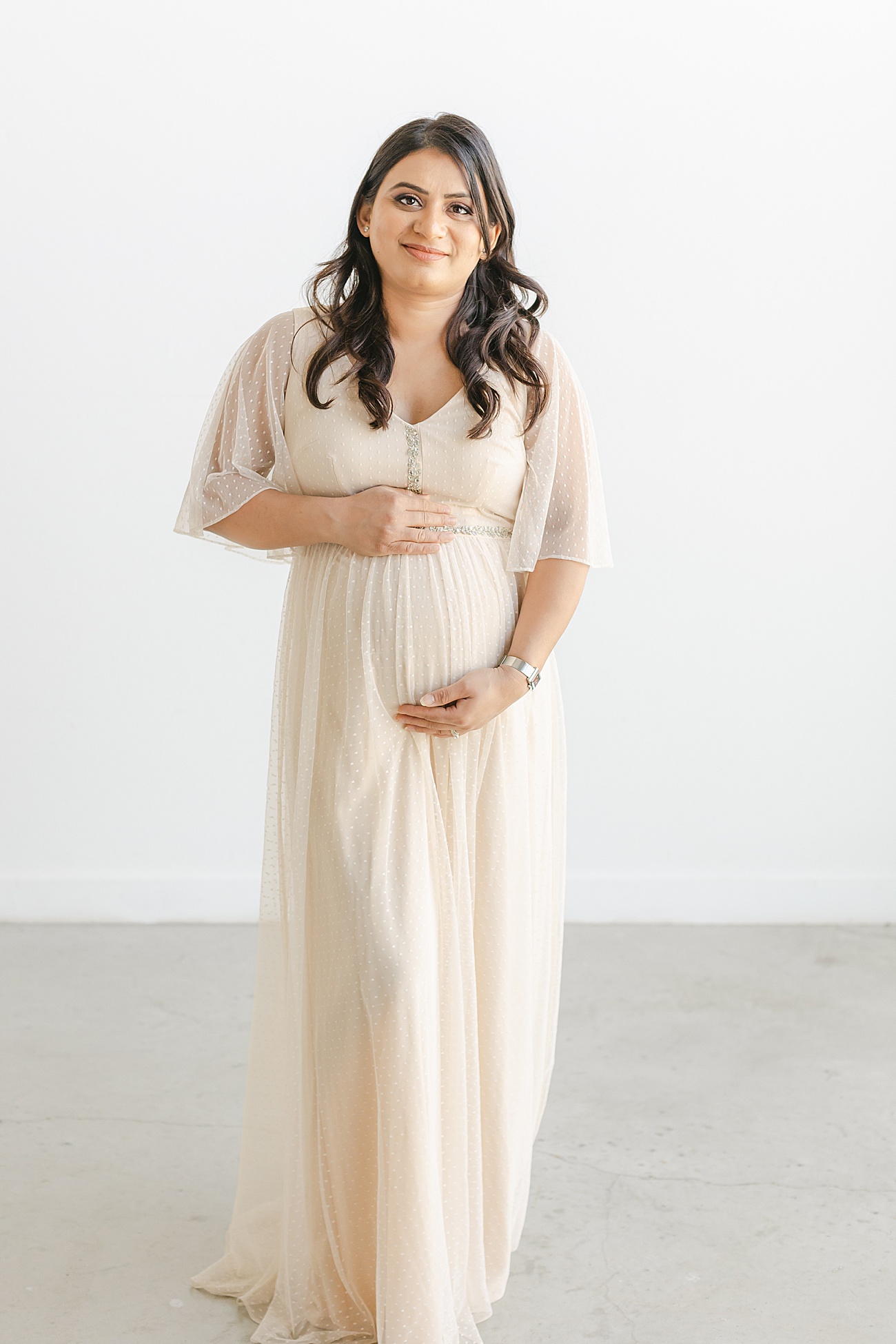Photo of Mama-to-be hugging baby bump during gender reveal session with Sana Ahmed Photography.
