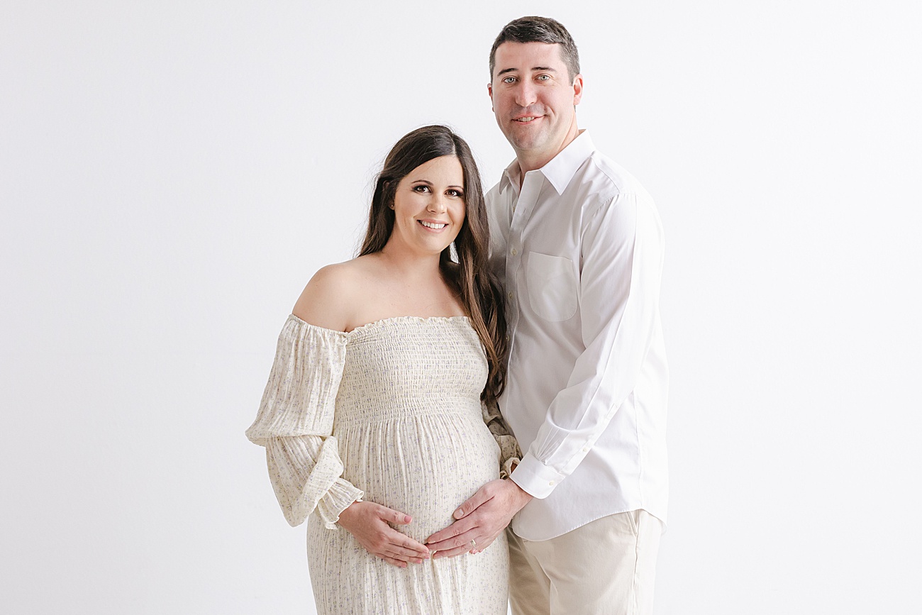 Classic maternity portrait with Mom and Dad smiling at camera during maternity session. Photo by Sana Ahmed Photography.