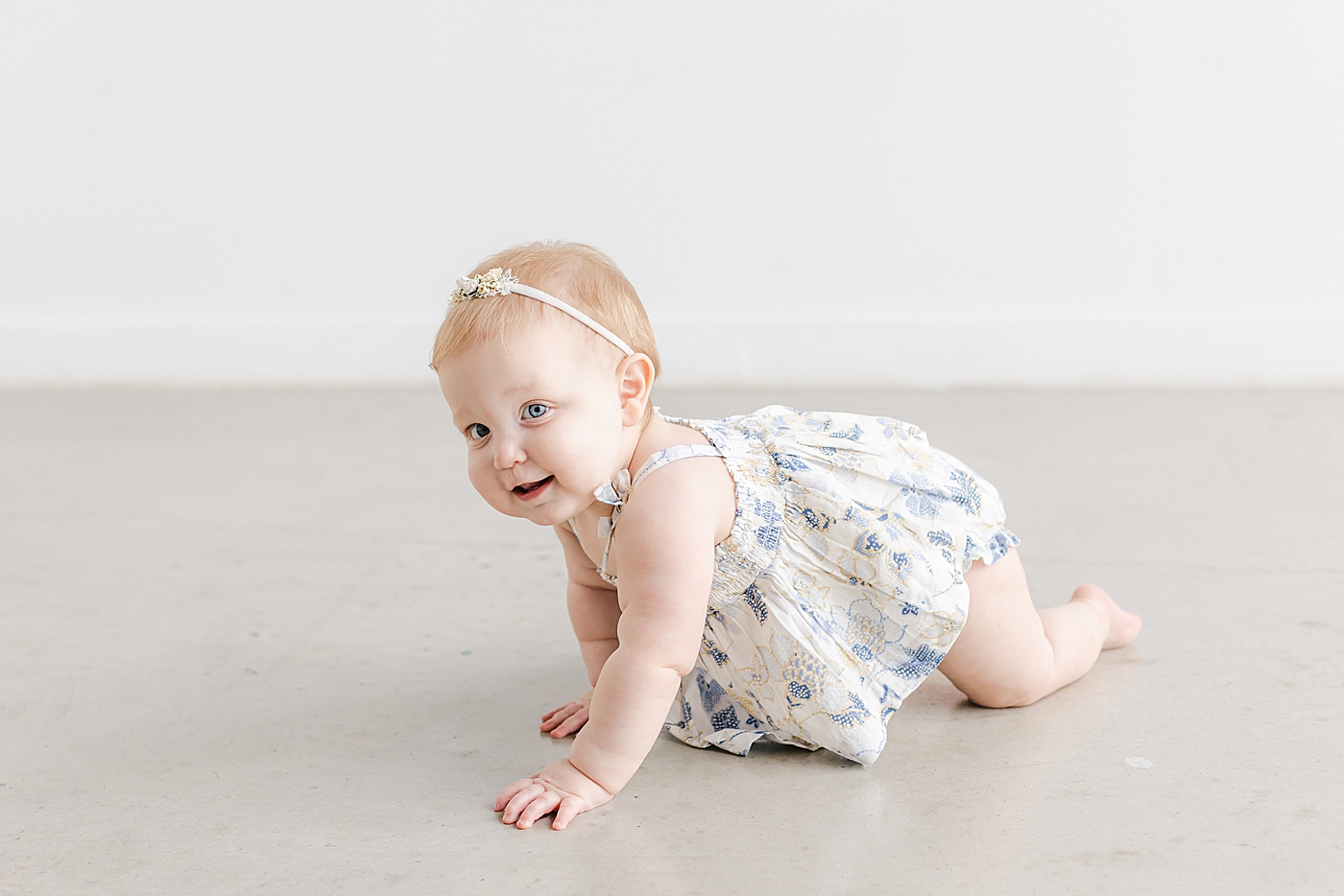 Baby girl in a cream and blue dress crawling | Sana Ahmed Photography