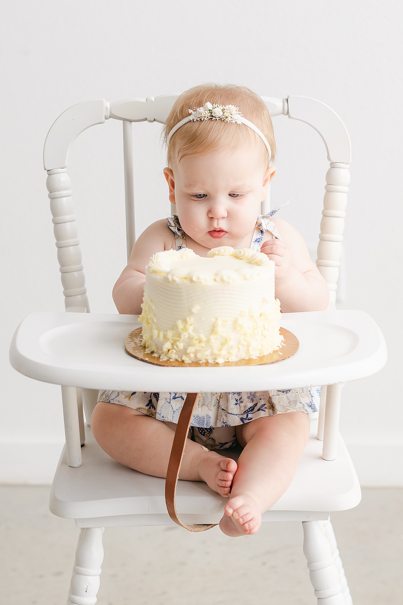 Baby girl in a highchair eating her smash cake | Sana Ahmed Photography