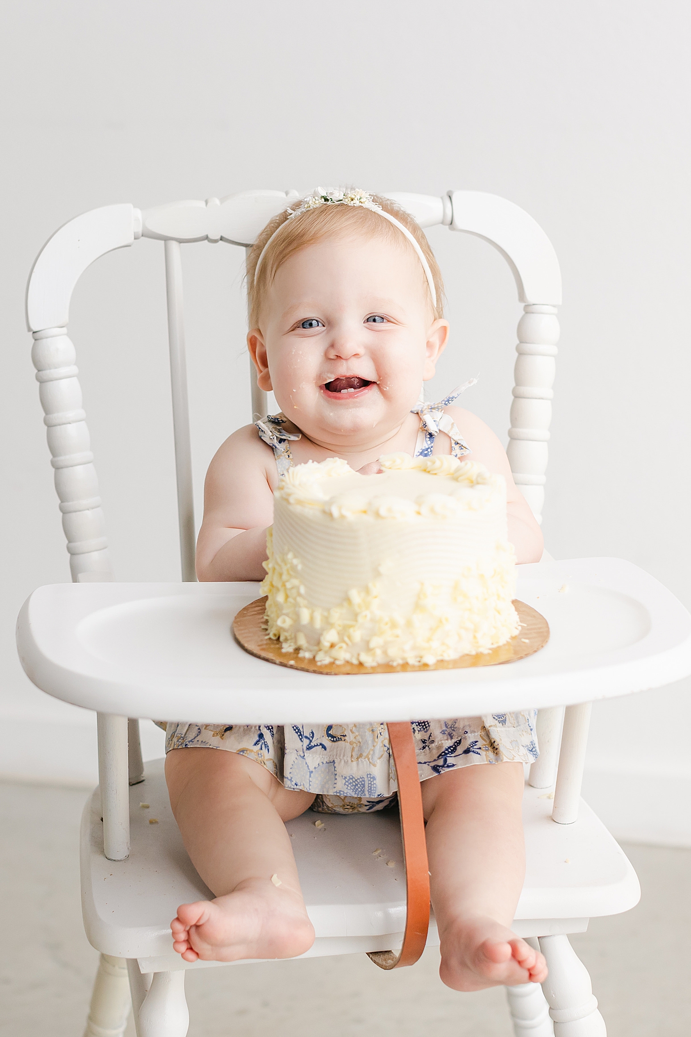 Baby girl smiling in a highchair during her one year milestone session | Sana Ahmed Photography