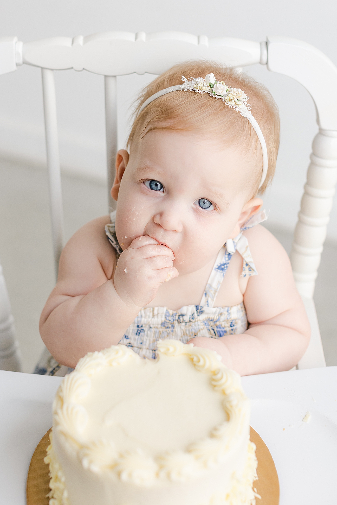 Baby girl with blue eyes eating cake during her one year milestone session | Sana Ahmed Photography
