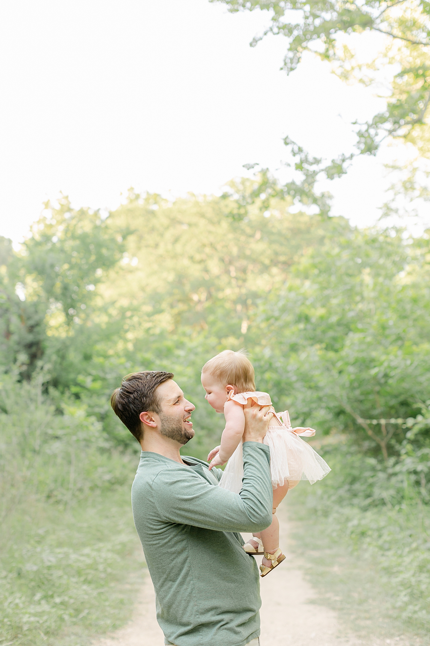 Dad in a green shirt holding his baby girl in a peach dress | Sana Ahmed Photography