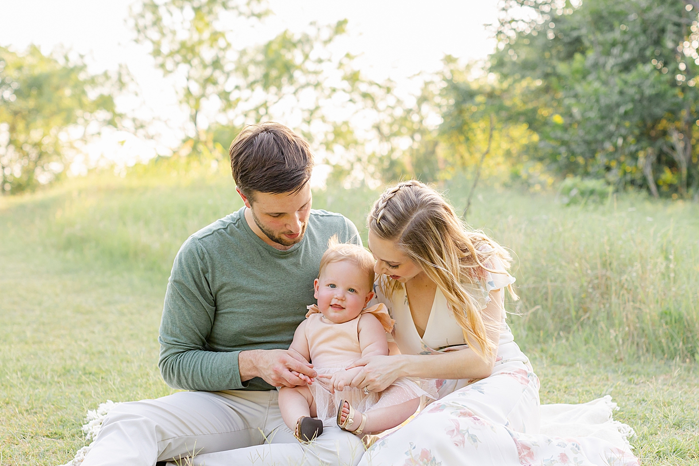 Mom and dad sitting in a field with their baby girl | Sana Ahmed Photography