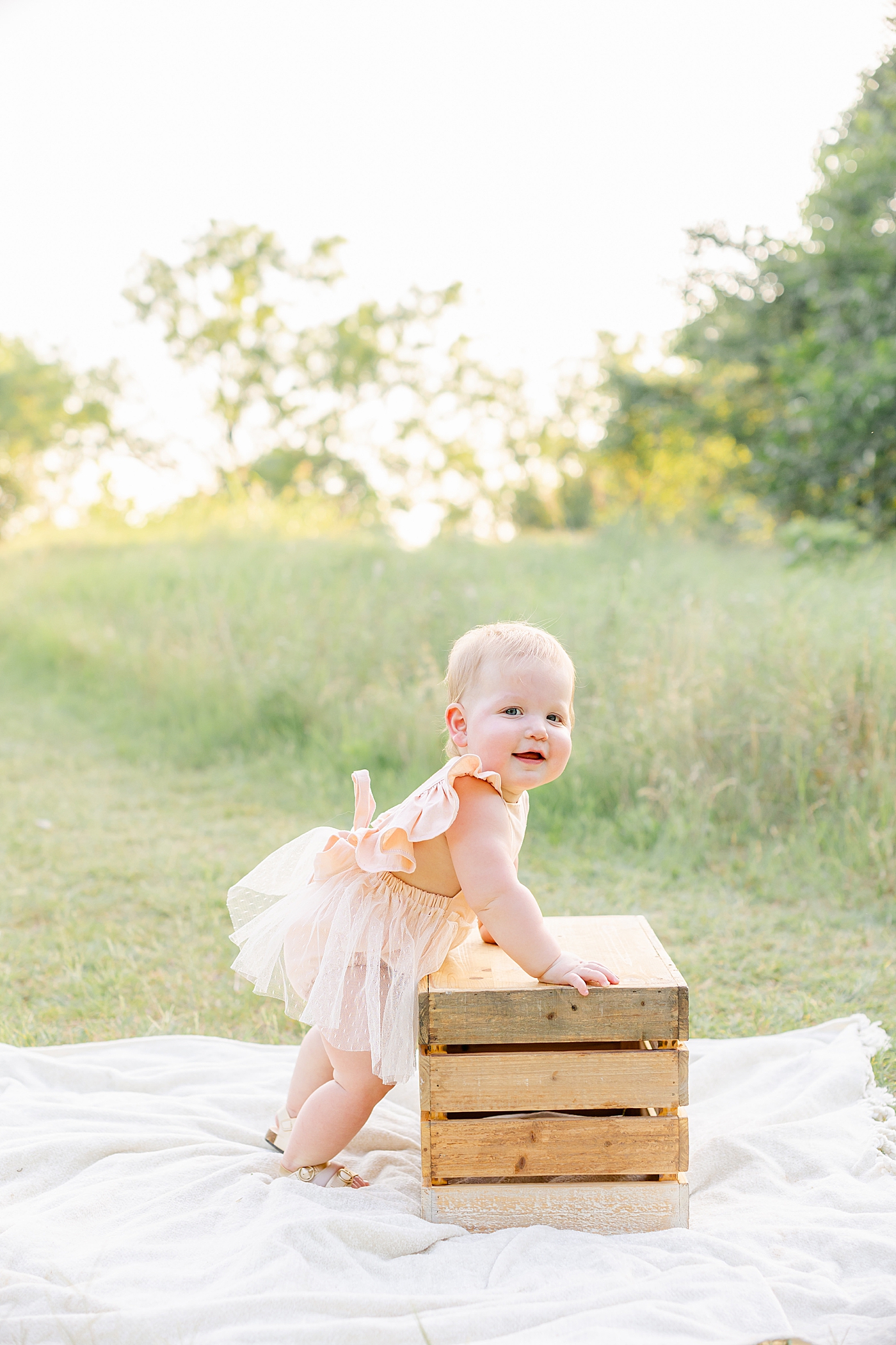 Baby girl standing with a box in a field during her one year milestone session | Sana Ahmed Photography
