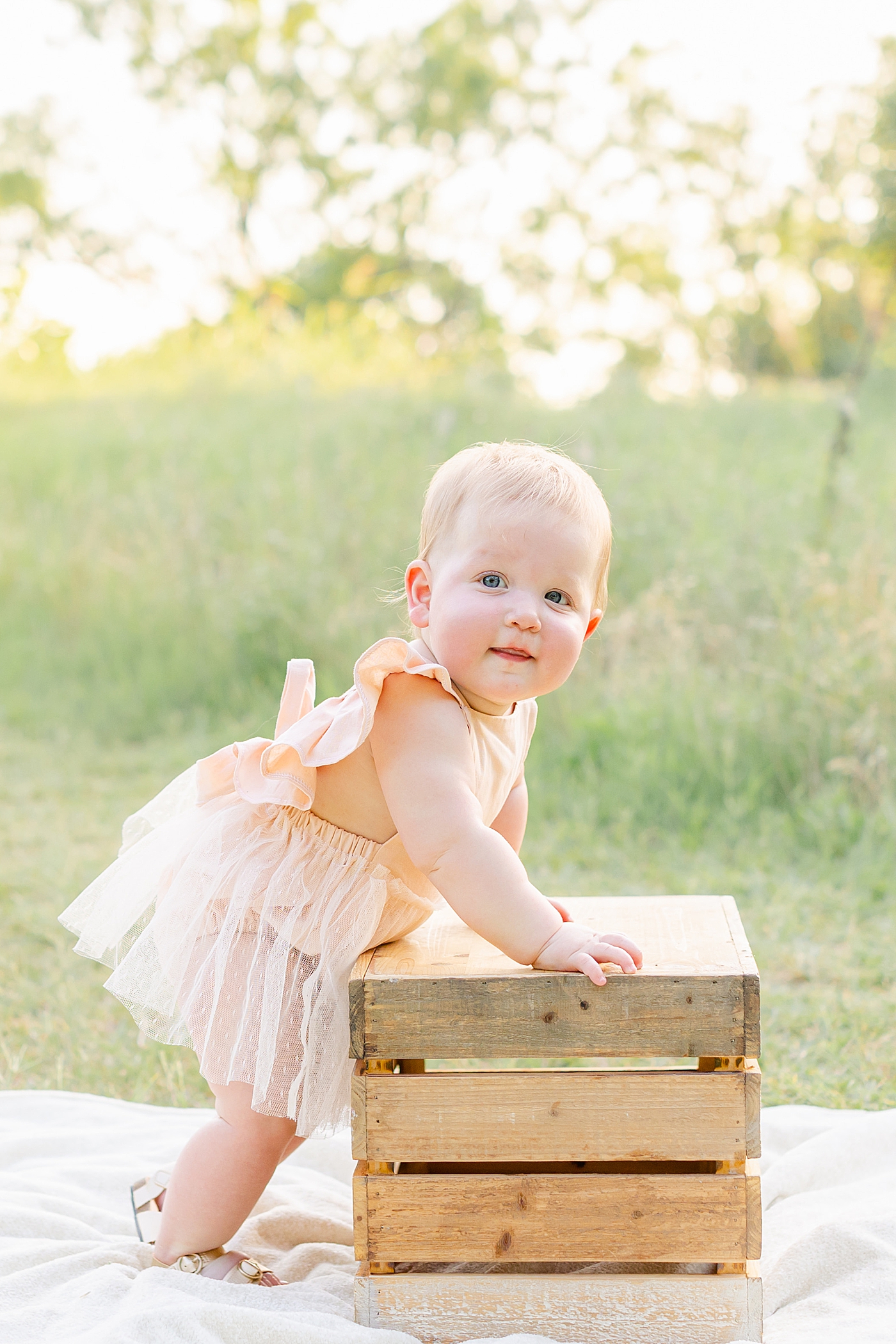 Baby girl holding onto a box during her one year milestone session | Sana Ahmed Photography