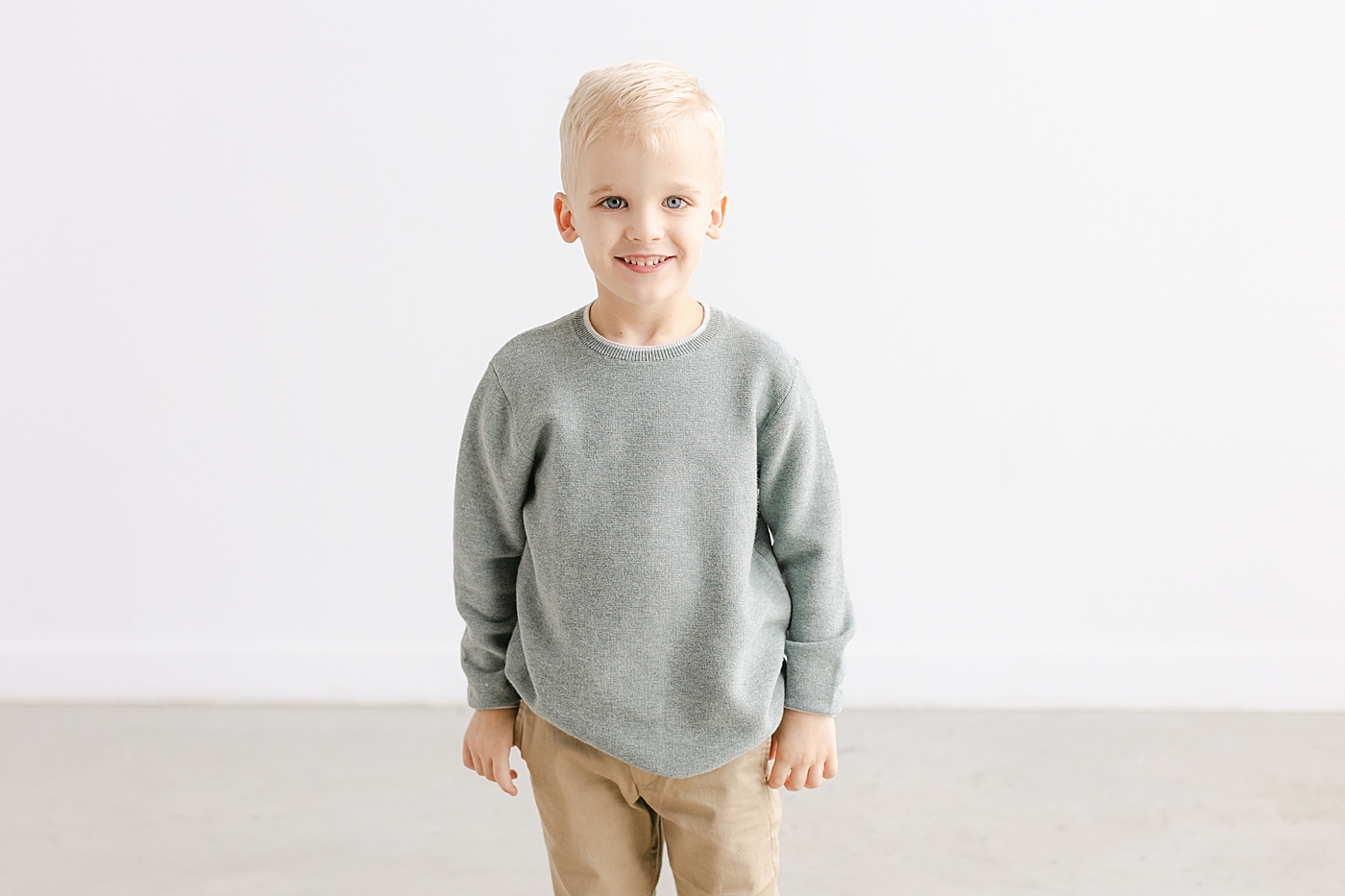 Little blonde boy in gray shirt smiling | Photo by Sana Ahmed Photography