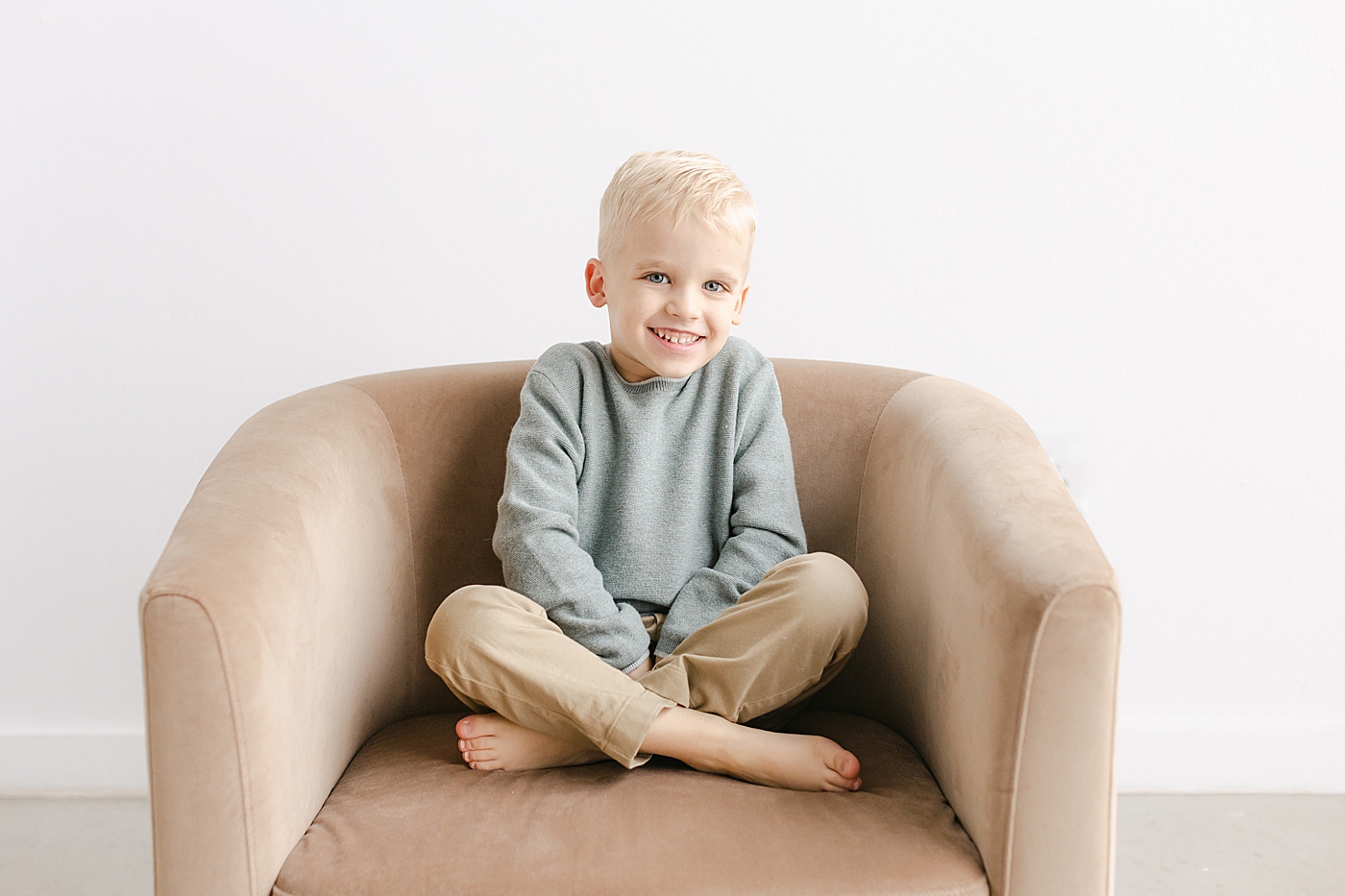 Little boy sitting in a brown chair during playful family studio session in Austin | Photo by Sana Ahmed Photography