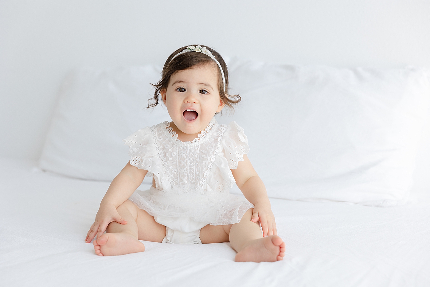Baby girl in a white dress making a surprised face | Image by Sana Ahmed Photography