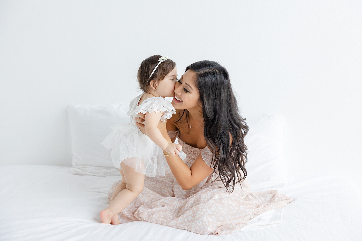 Baby girl giving mom a kiss on the cheek | Image by Sana Ahmed Photography