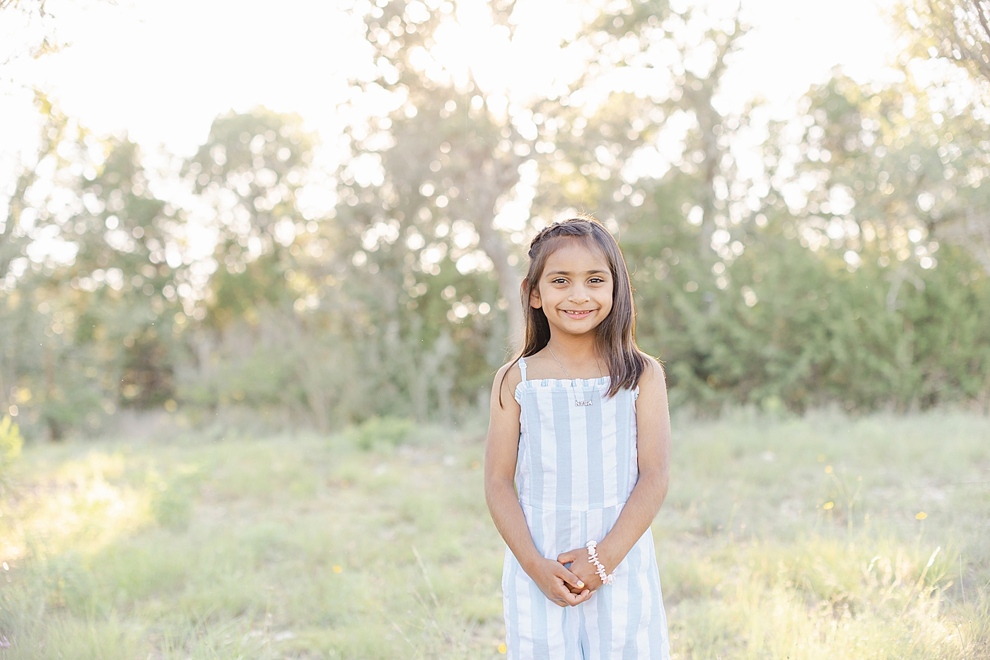 Little girl in a striped dress smiling | Photo by Sana Ahmed Photography