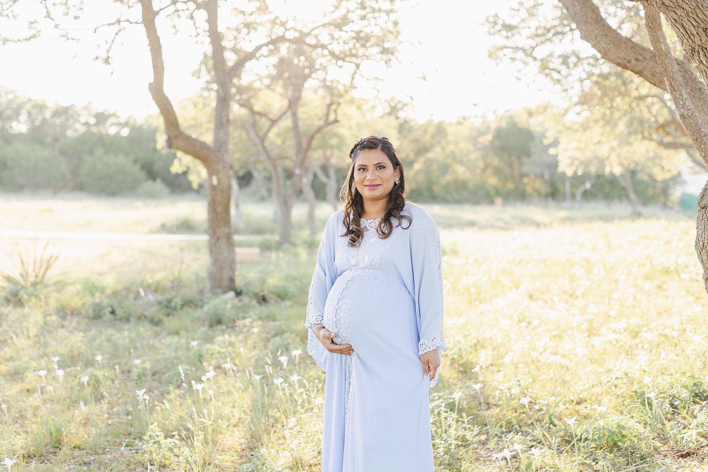Mom to be in a blue dress in a field | Photo by Sana Ahmed Photography