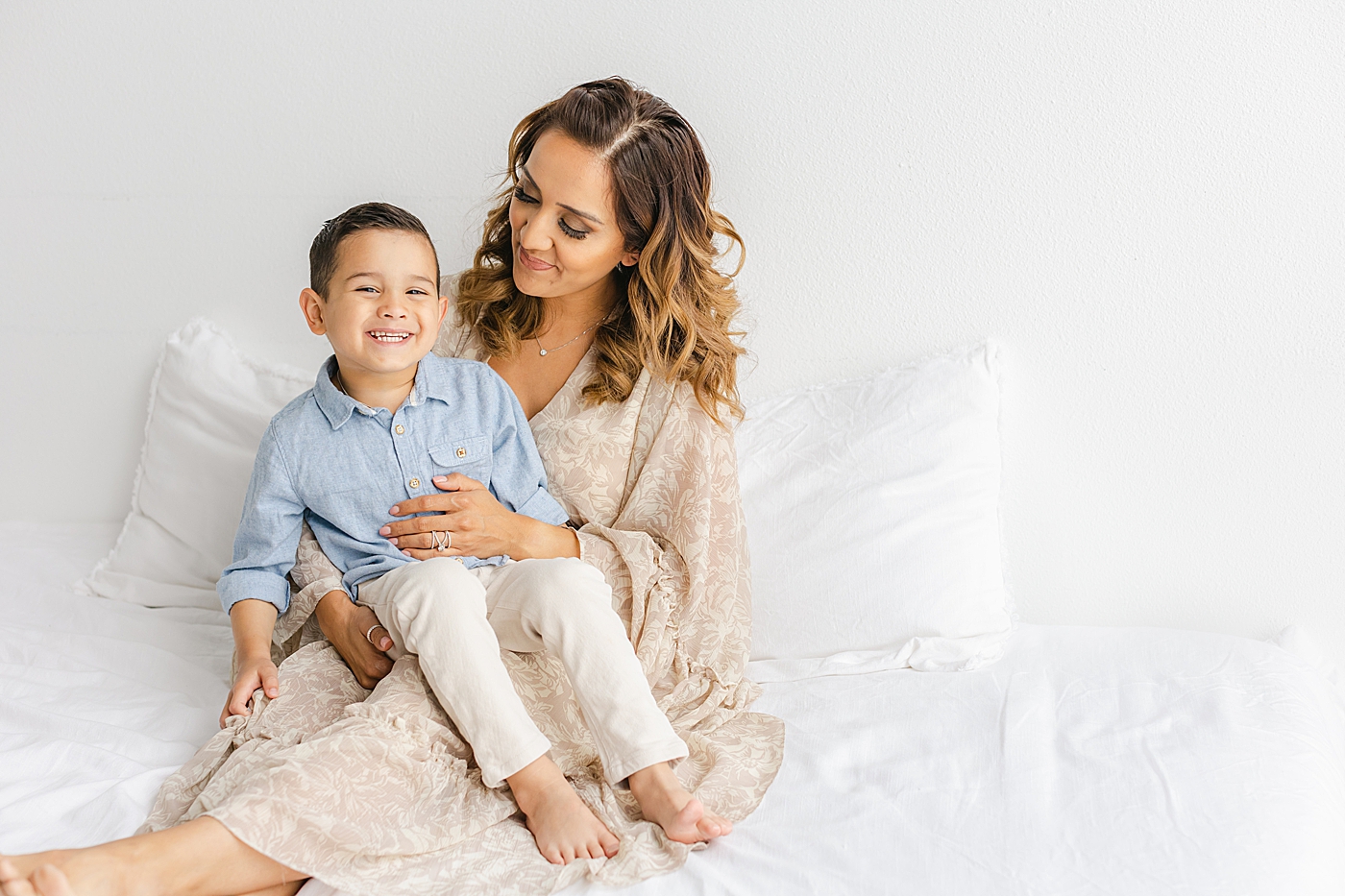 Mom sitting with her little boy on a white bed | Photo by Sana Ahmed Photography