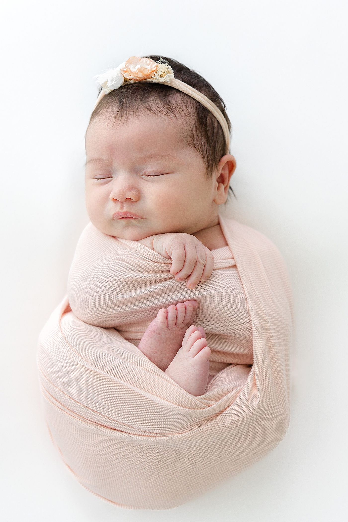 Sleeping baby in headband and swaddle during her Austin Studio Newborn Session | Photo by Sana Ahmed Photography