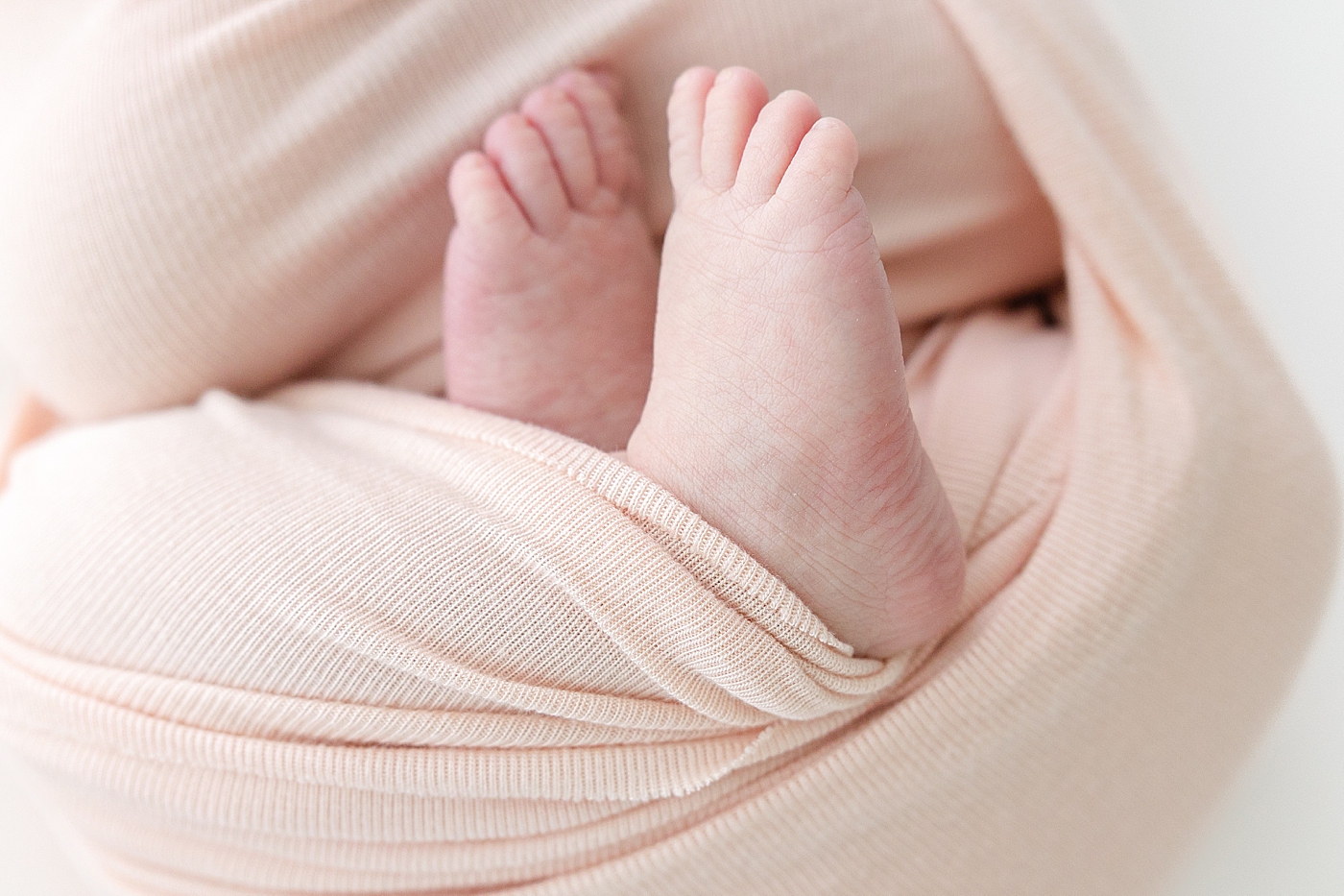 Detail of newborn baby feet wrapped in swaddle | Photo by Sana Ahmed Photography