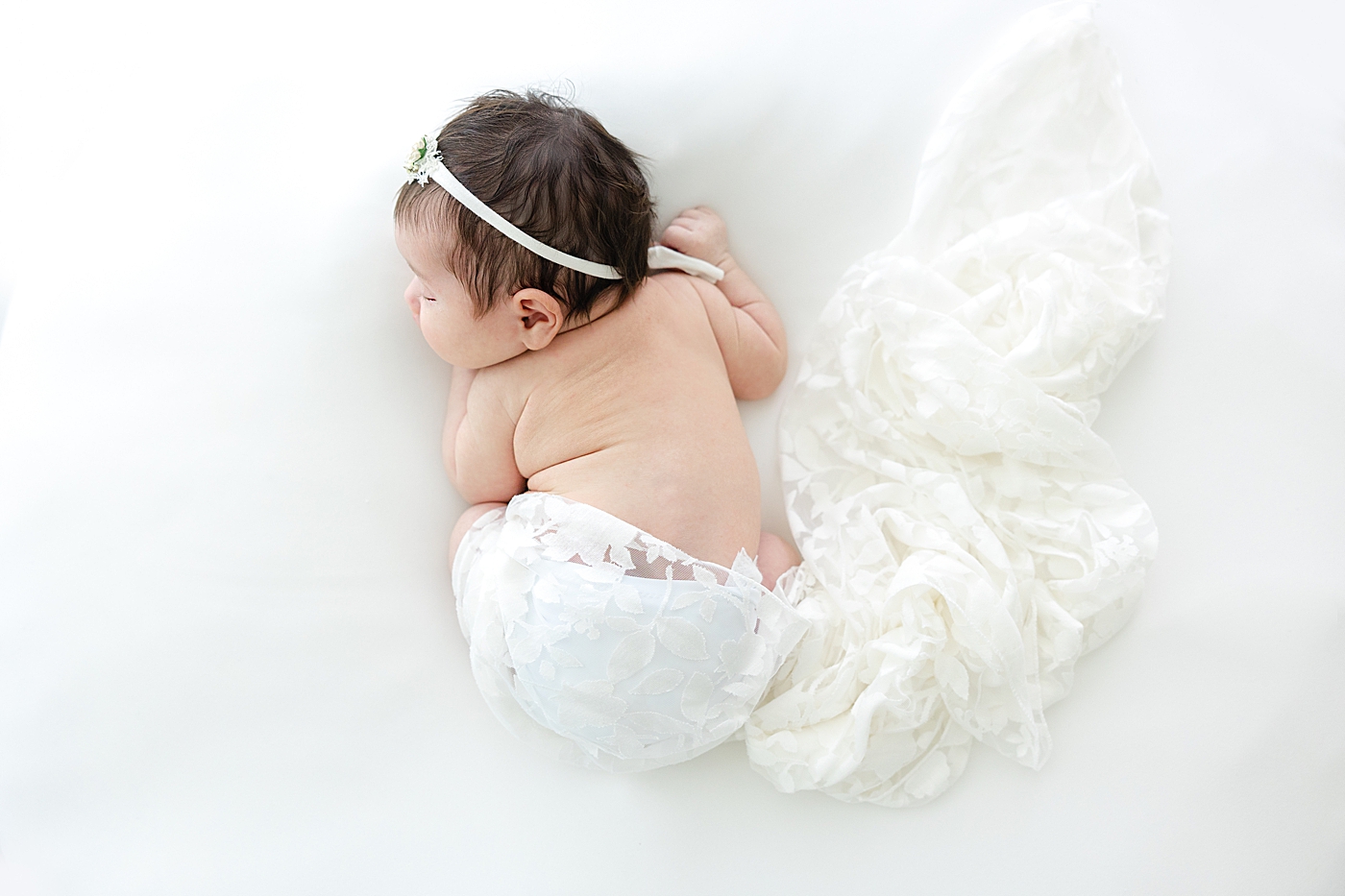 Newborn baby girl wrapped in a white lace swaddle during her Austin Studio Newborn Session | Photo by Sana Ahmed Photography