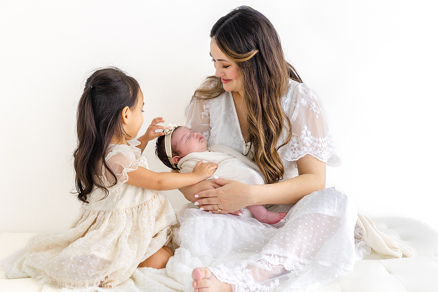 Mom and baby doting on their newborn during her Austin Studio Newborn Session | Photo by Sana Ahmed Photography