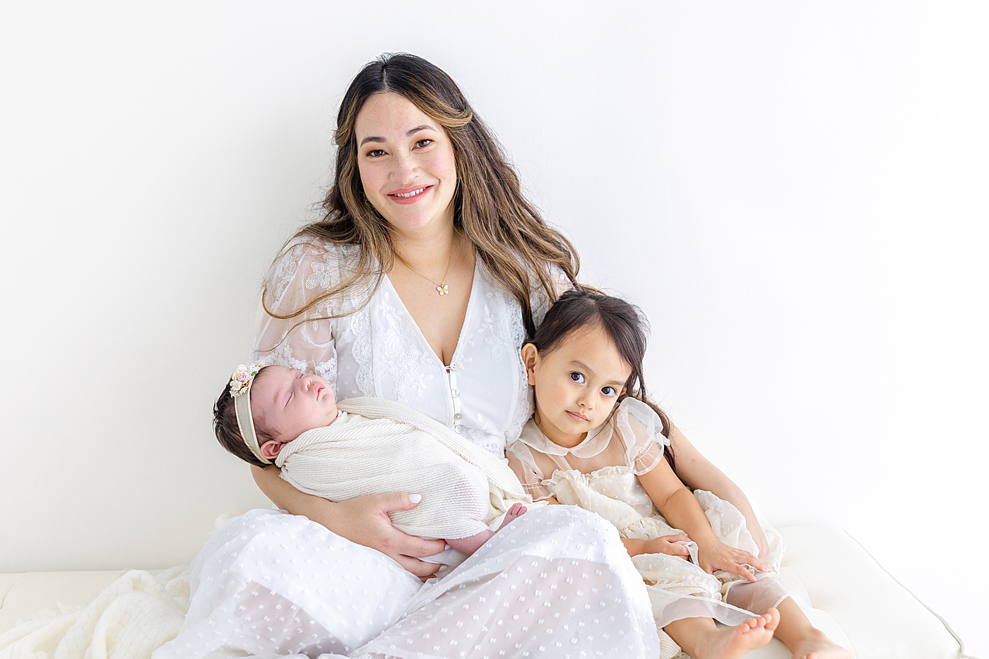 Mom holding her two daughters during her Austin Studio Newborn Session | Photo by Sana Ahmed Photography
