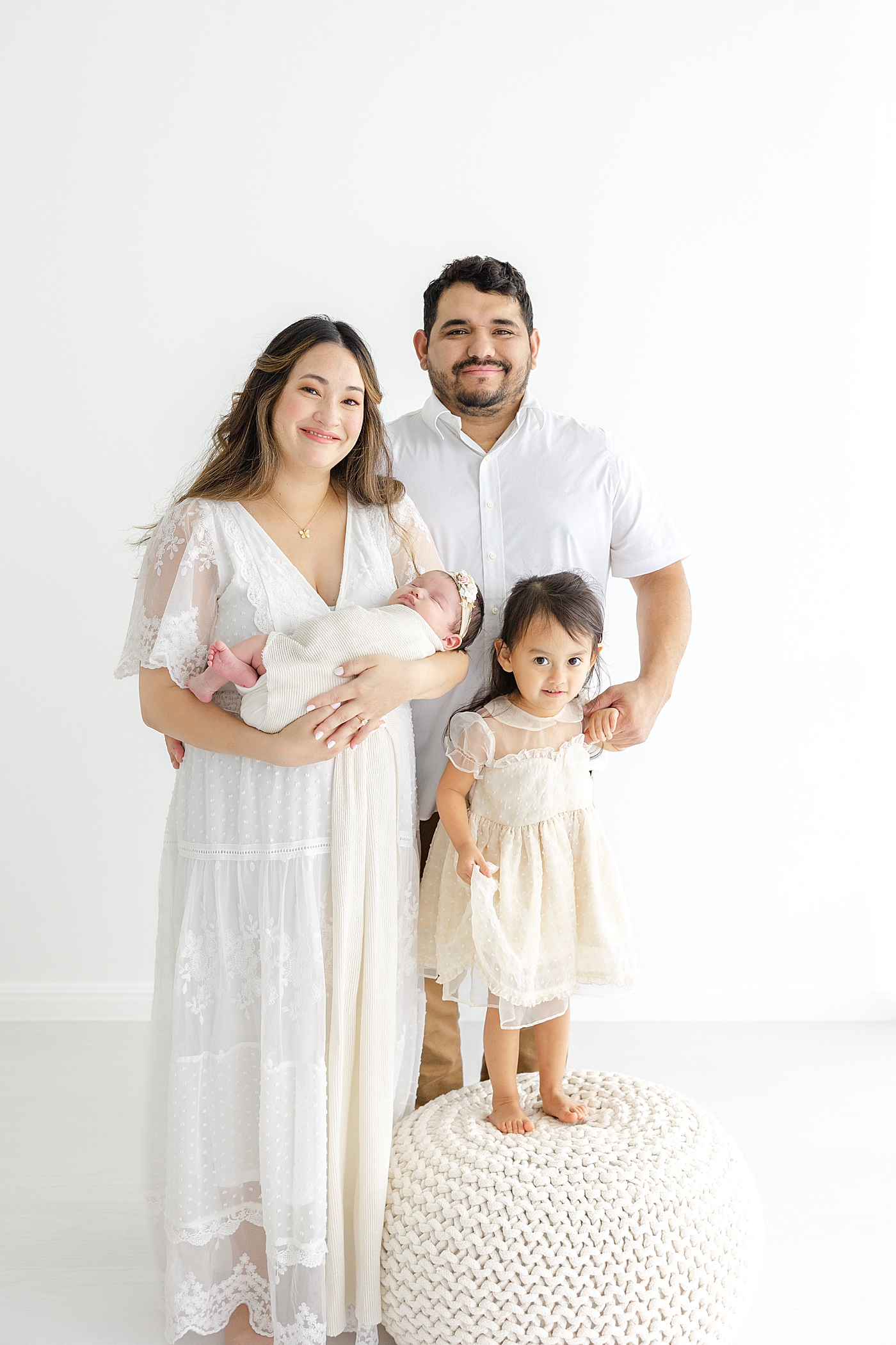 Family of four holding their new baby during her Austin Studio Newborn Session | Photo by Sana Ahmed Photography