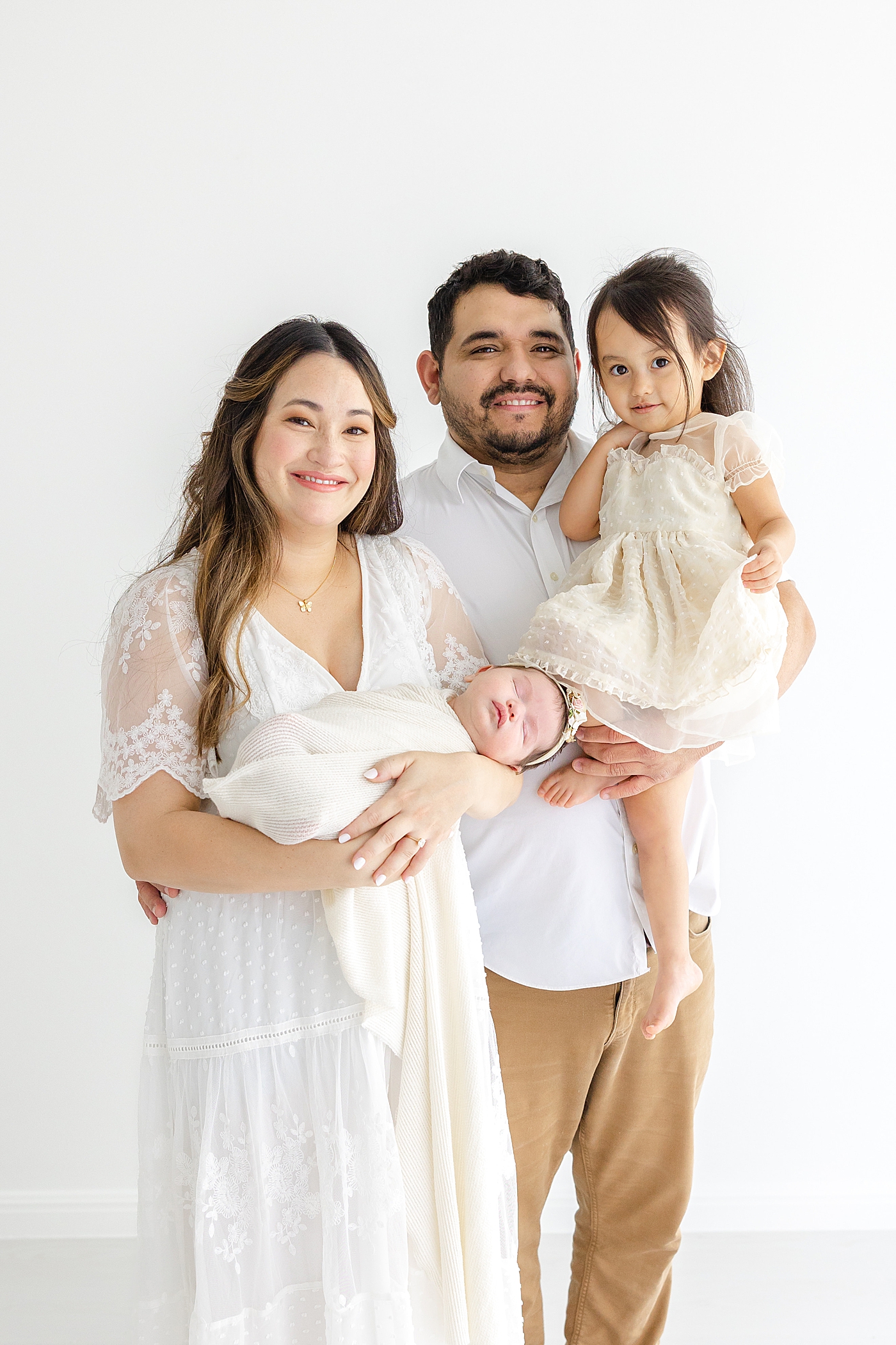 Family holding their new baby during her Austin Studio Newborn Session | Photo by Sana Ahmed Photography