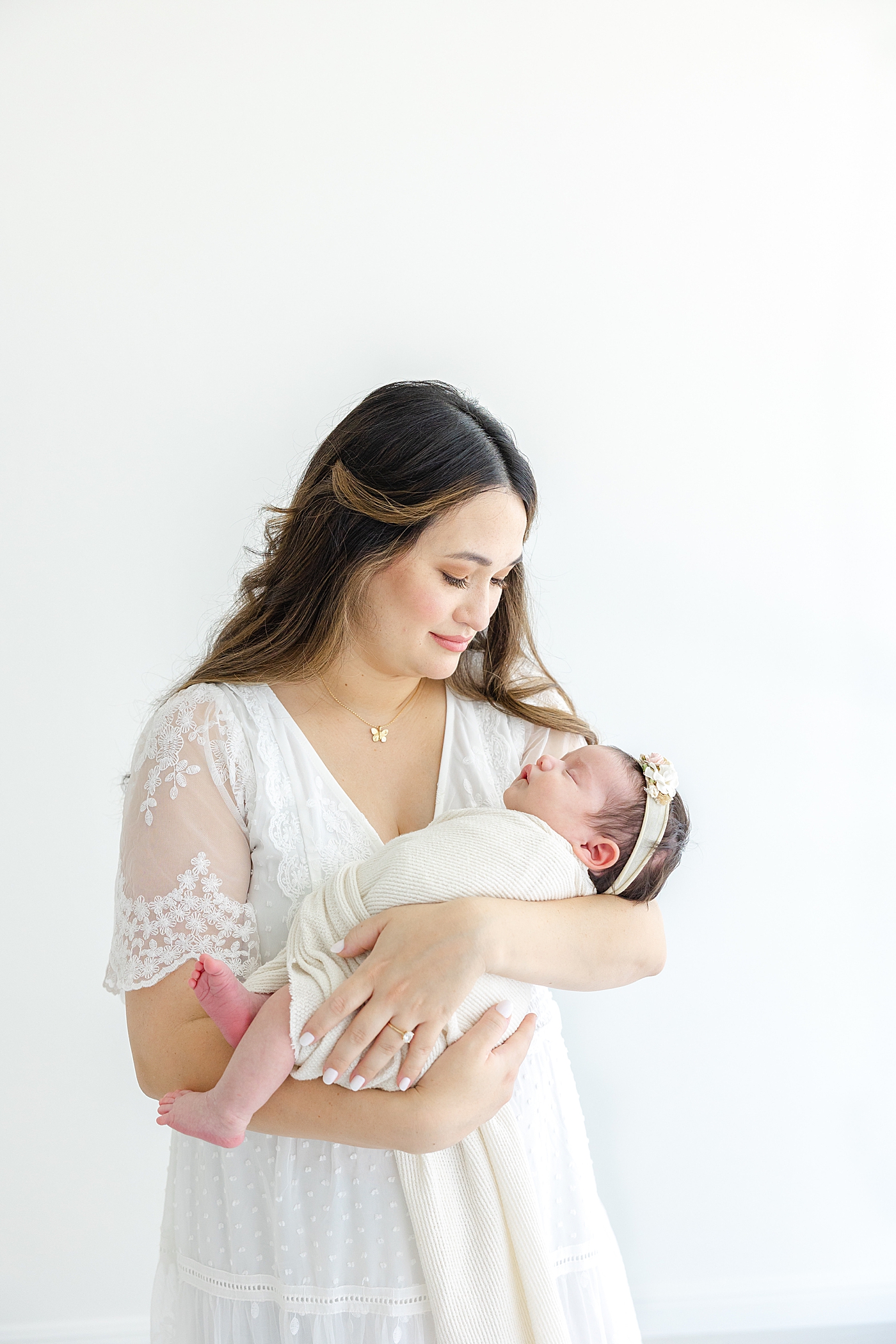 Mom holding her newborn baby girl during her Austin Studio Newborn Session | Photo by Sana Ahmed Photography
