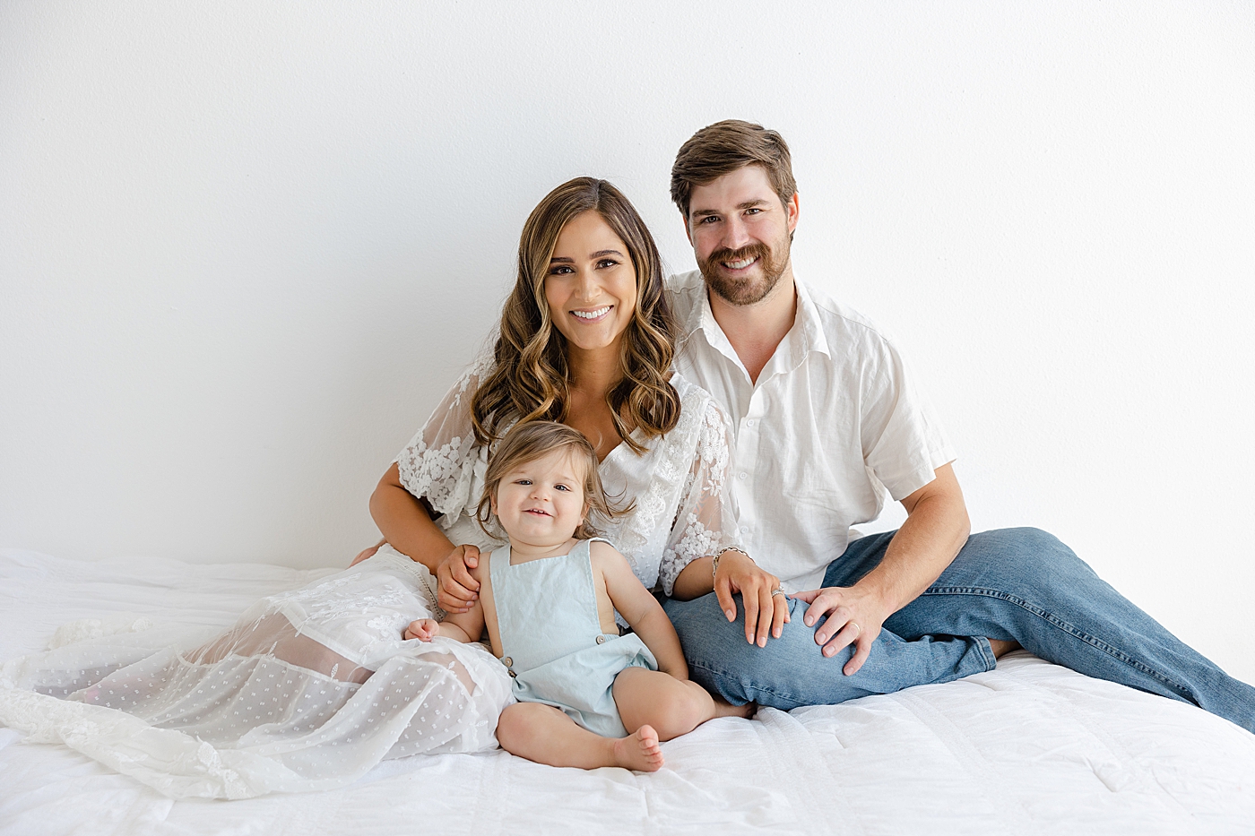 Family of three sitting on a bed during their Studio Family Session | Photo by Sana Ahmed Photography