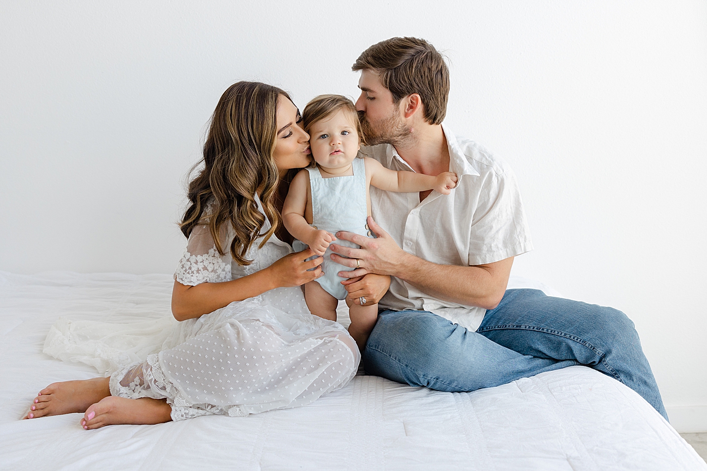 Mom and dad kissing their baby girl during their Studio Family Session | Photo by Sana Ahmed Photography
