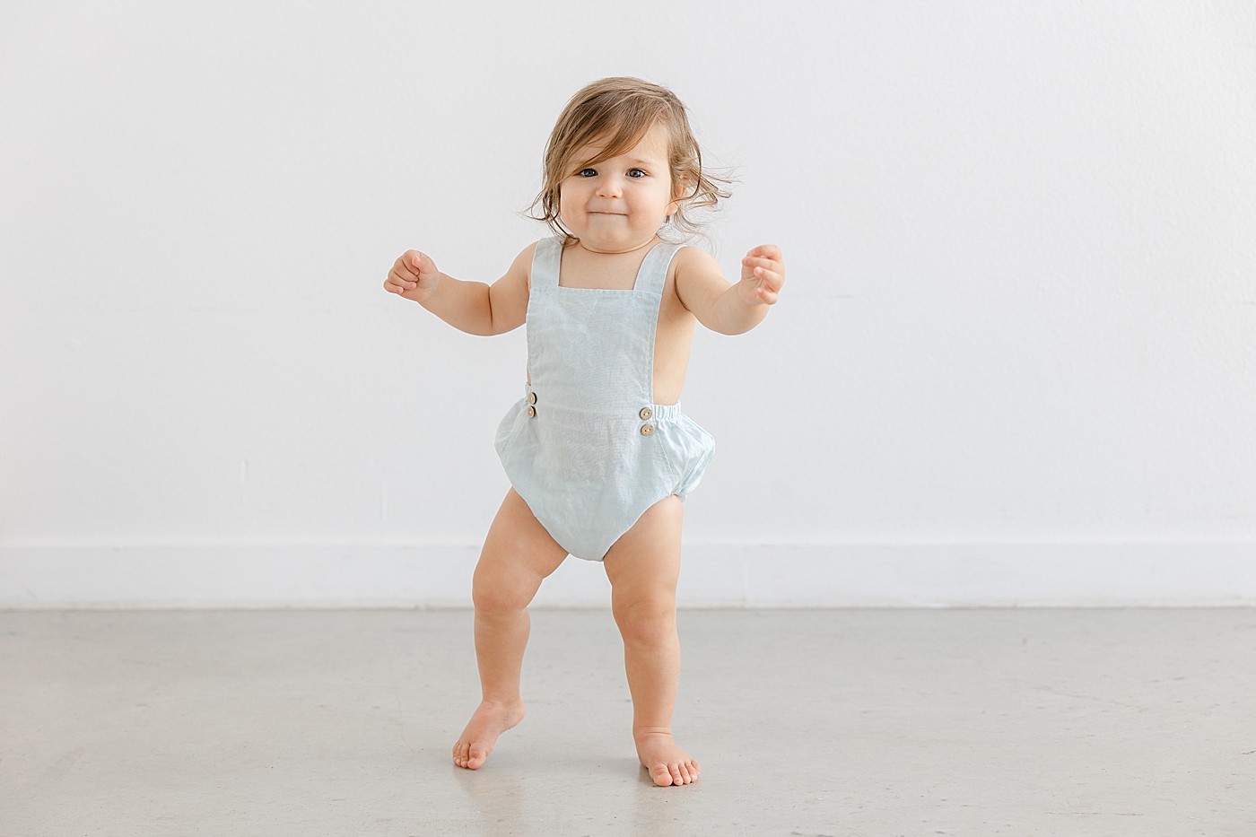 Baby girl in a romper practicing her walking | Photo by Sana Ahmed Photography