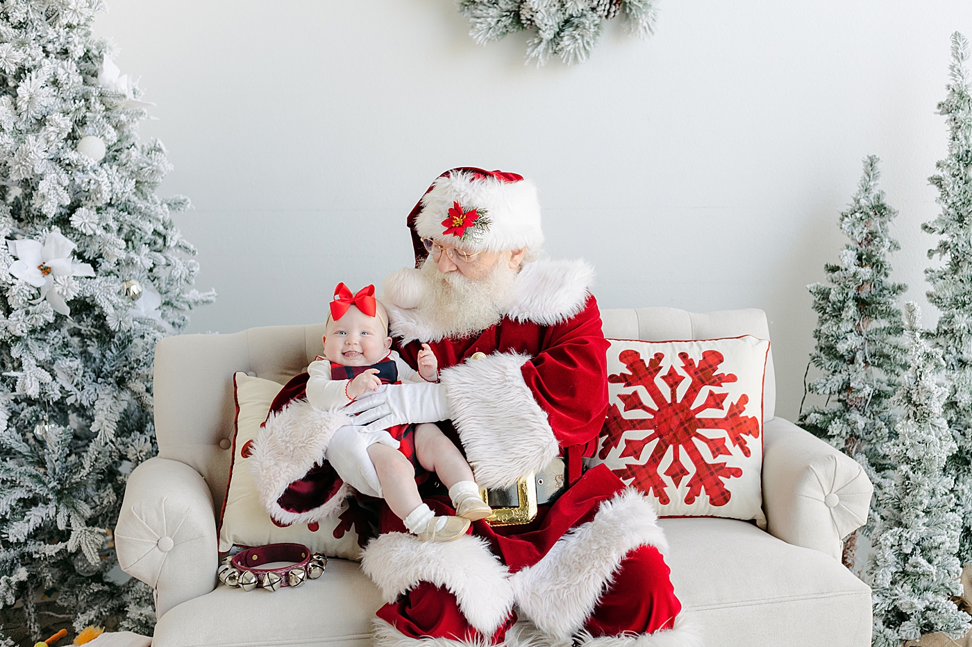 Baby girl in a red bow sitting with Santa | Images by Sana Ahmed Photography