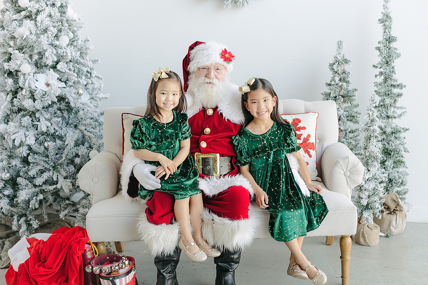 Sisters in green dresses sitting with Santa during Santa Sessions in Austin | Images by Sana Ahmed Photography