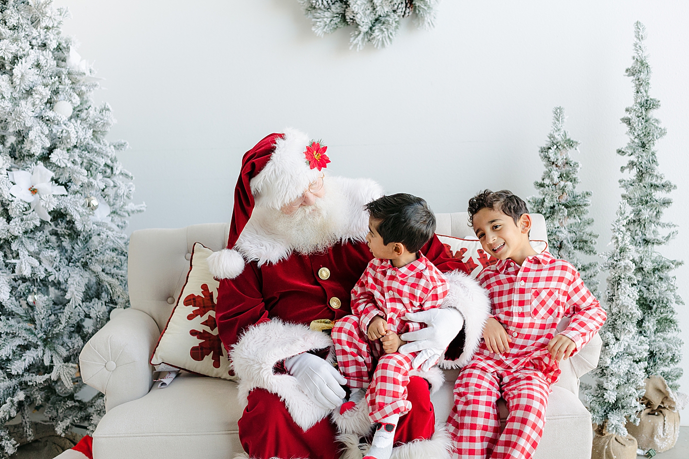 Brothers in red and white pajamas sitting with Santa | Images by Sana Ahmed Photography