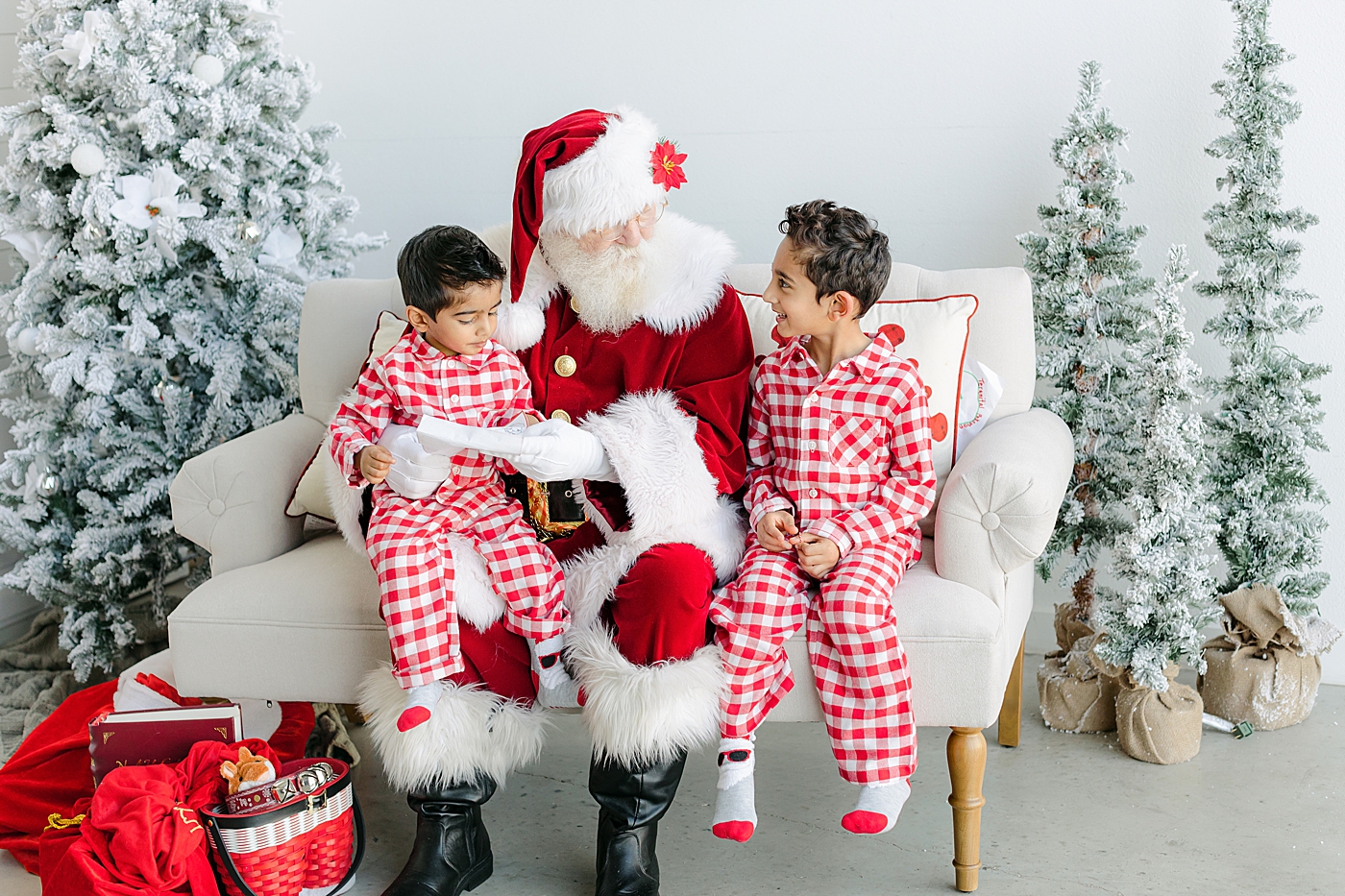 Brothers in red pajamas reading a book with Santa | Image by Sana Ahmed Photography
