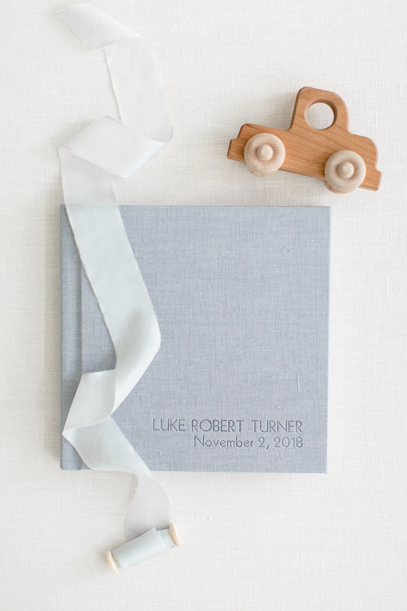 Gray album with ribbon and wooden toy | Sana Ahmed Photography