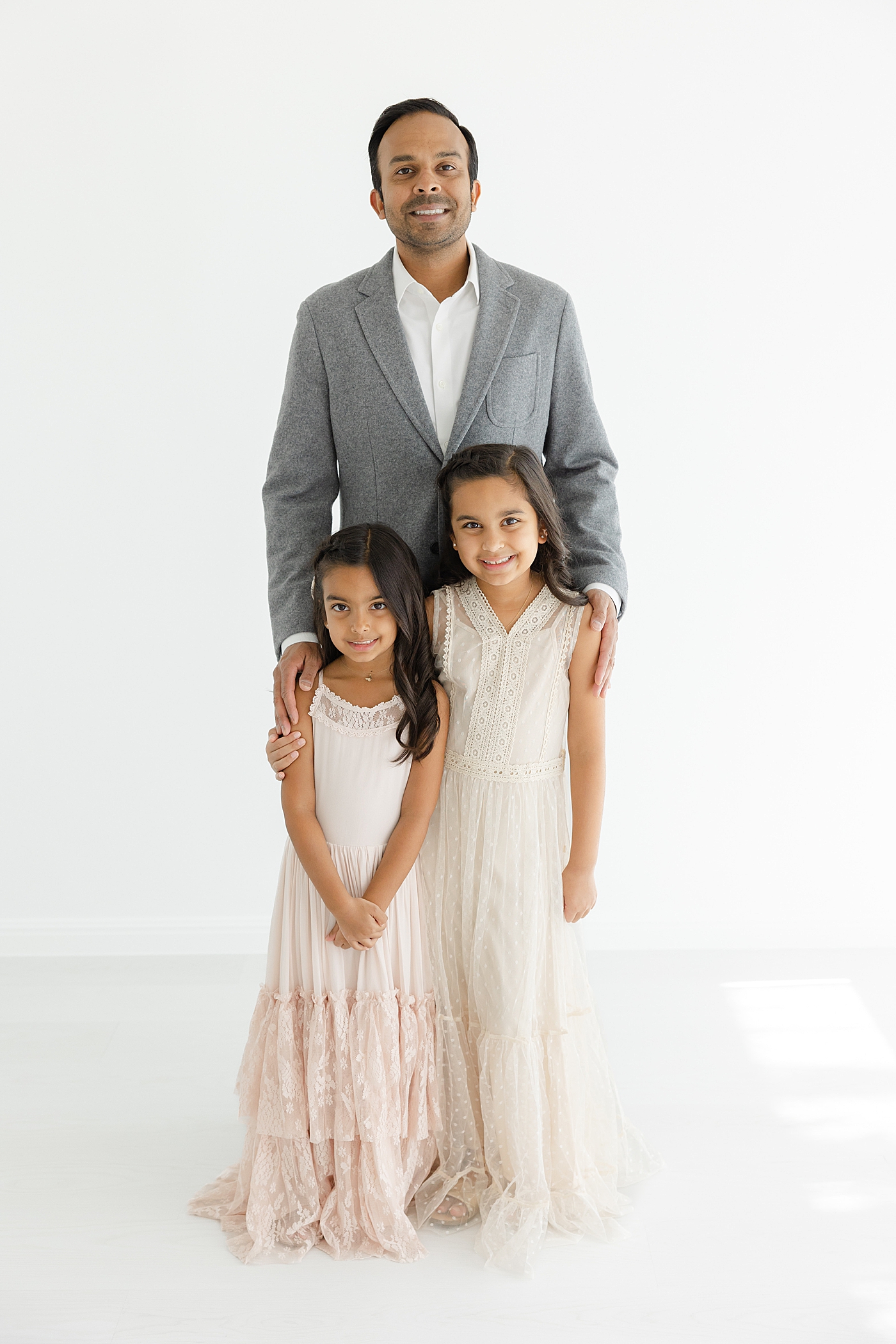 Dad posing with his two daughters in the studio | Image by Sana Ahmed Photography