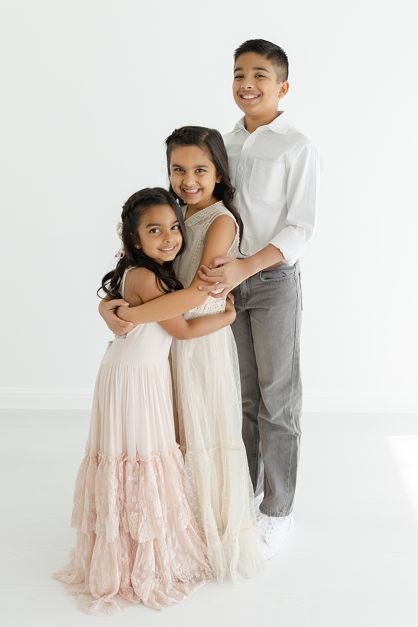 Three little kids hugging at the studio | Image by Sana Ahmed Photography