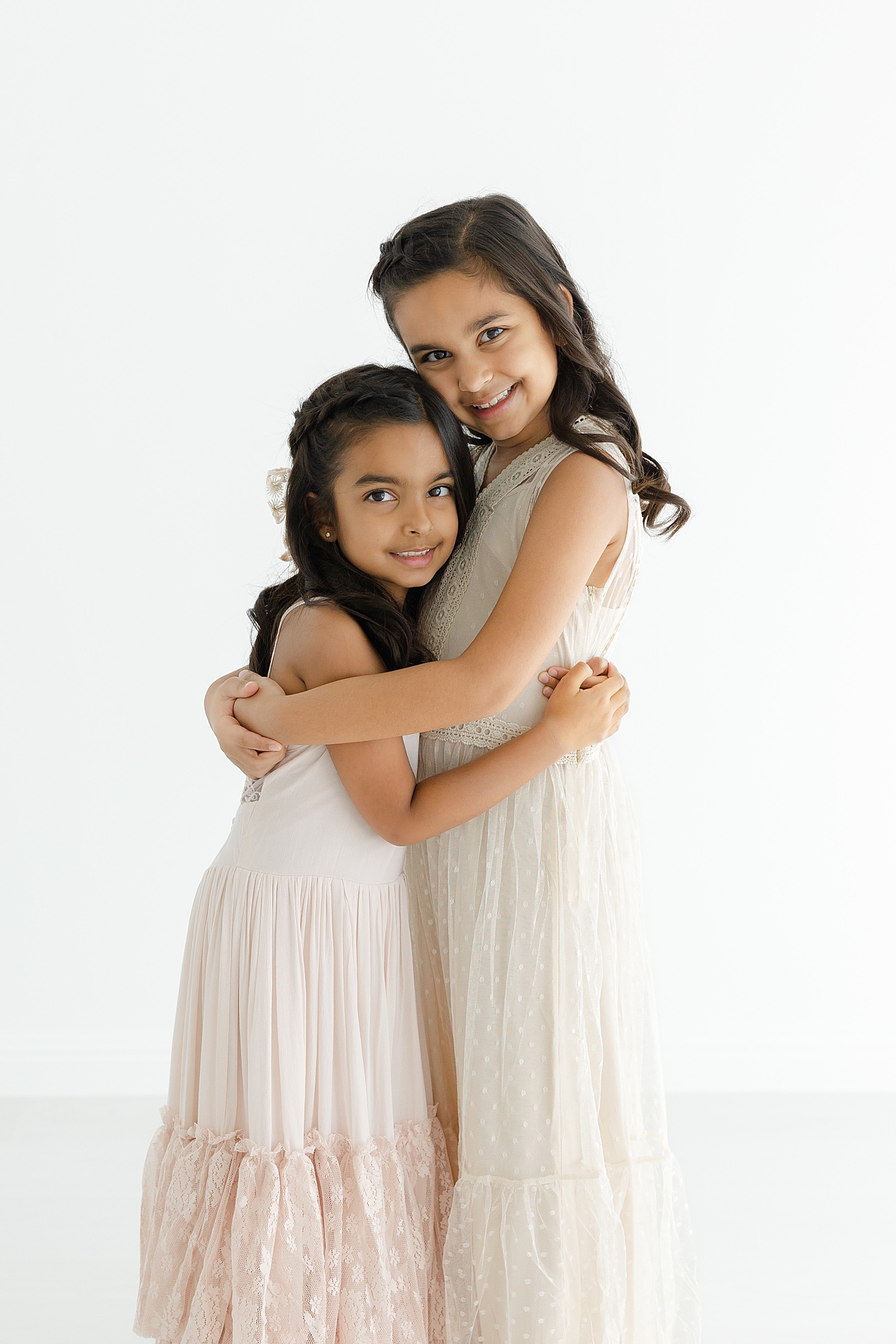 Sisters in pale pink maxi dresses hugging | Image by Sana Ahmed Photography