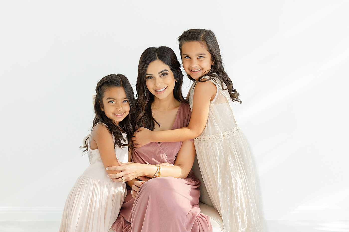 Mom hugging her two daughters in the studio | Image by Sana Ahmed Photography