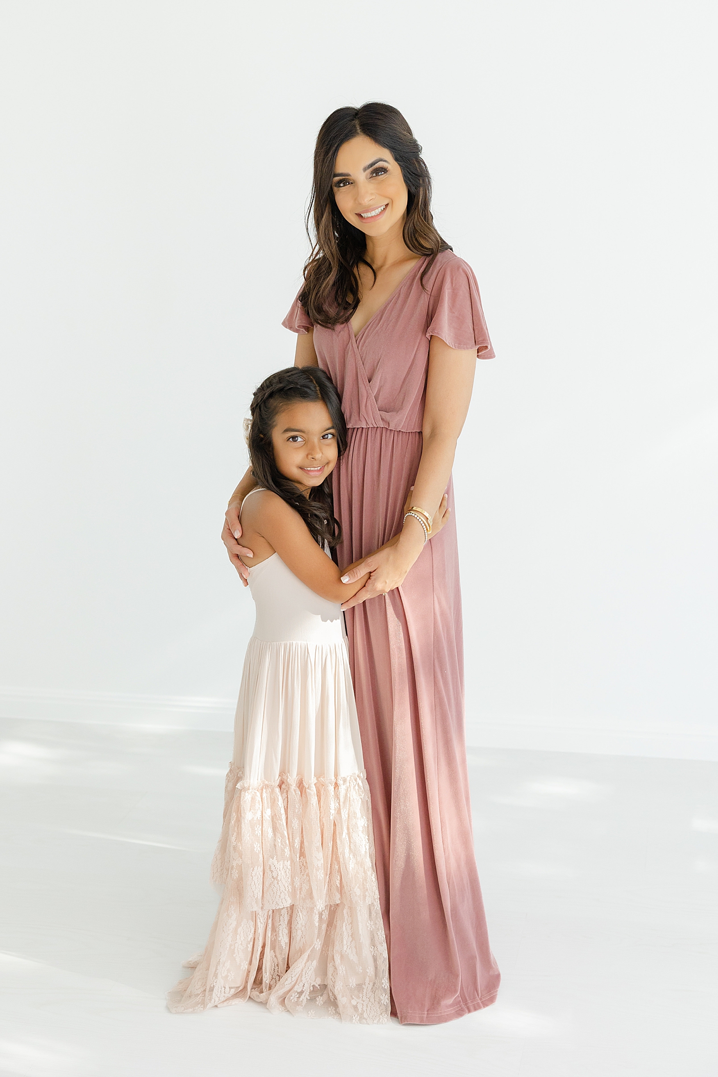 Mom in long pink dress hugging her daughter | Image by Sana Ahmed Photography
