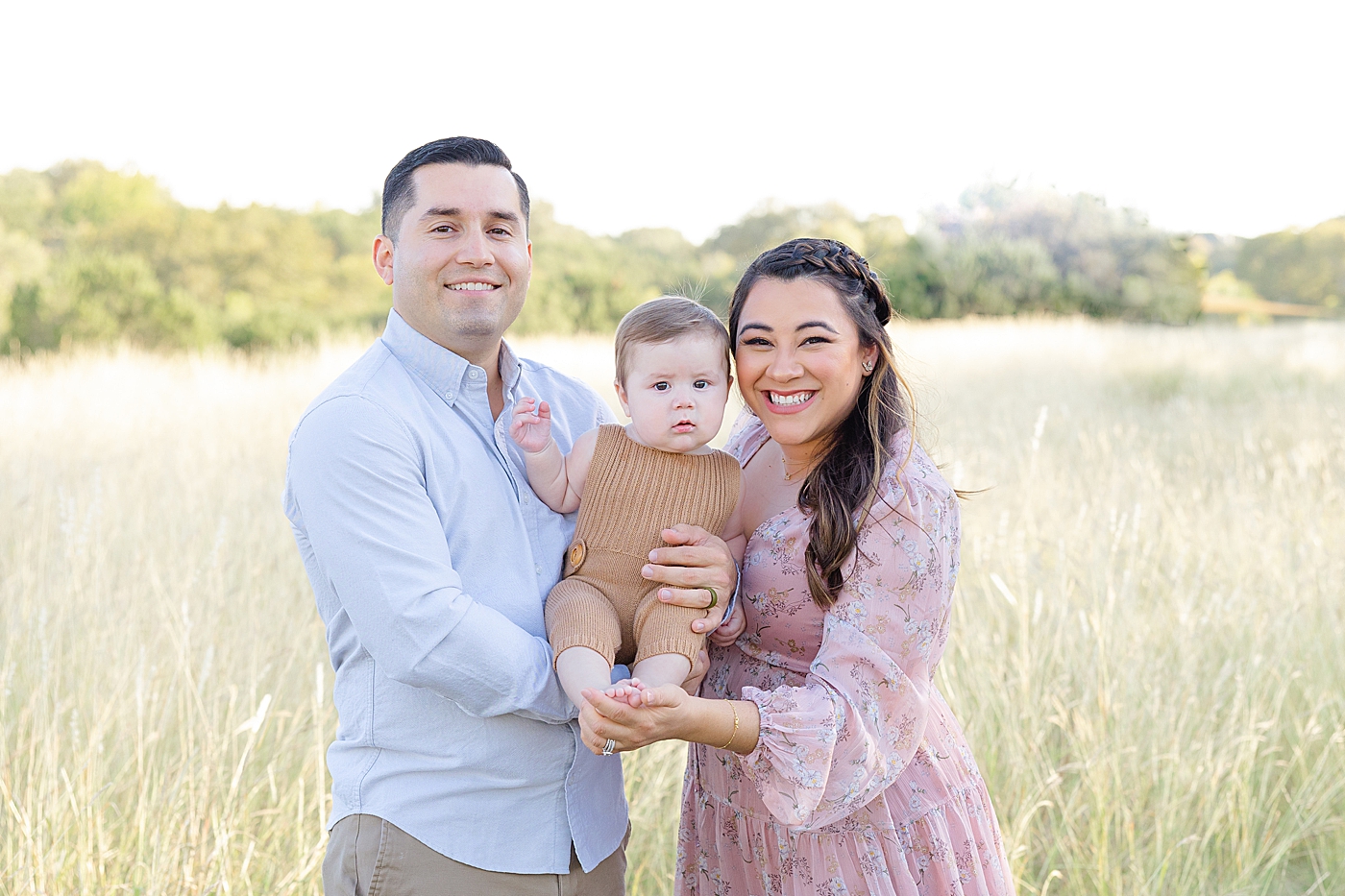 Family of three in a field during Six Month Milestone Session | Image by Sana Ahmed Photography