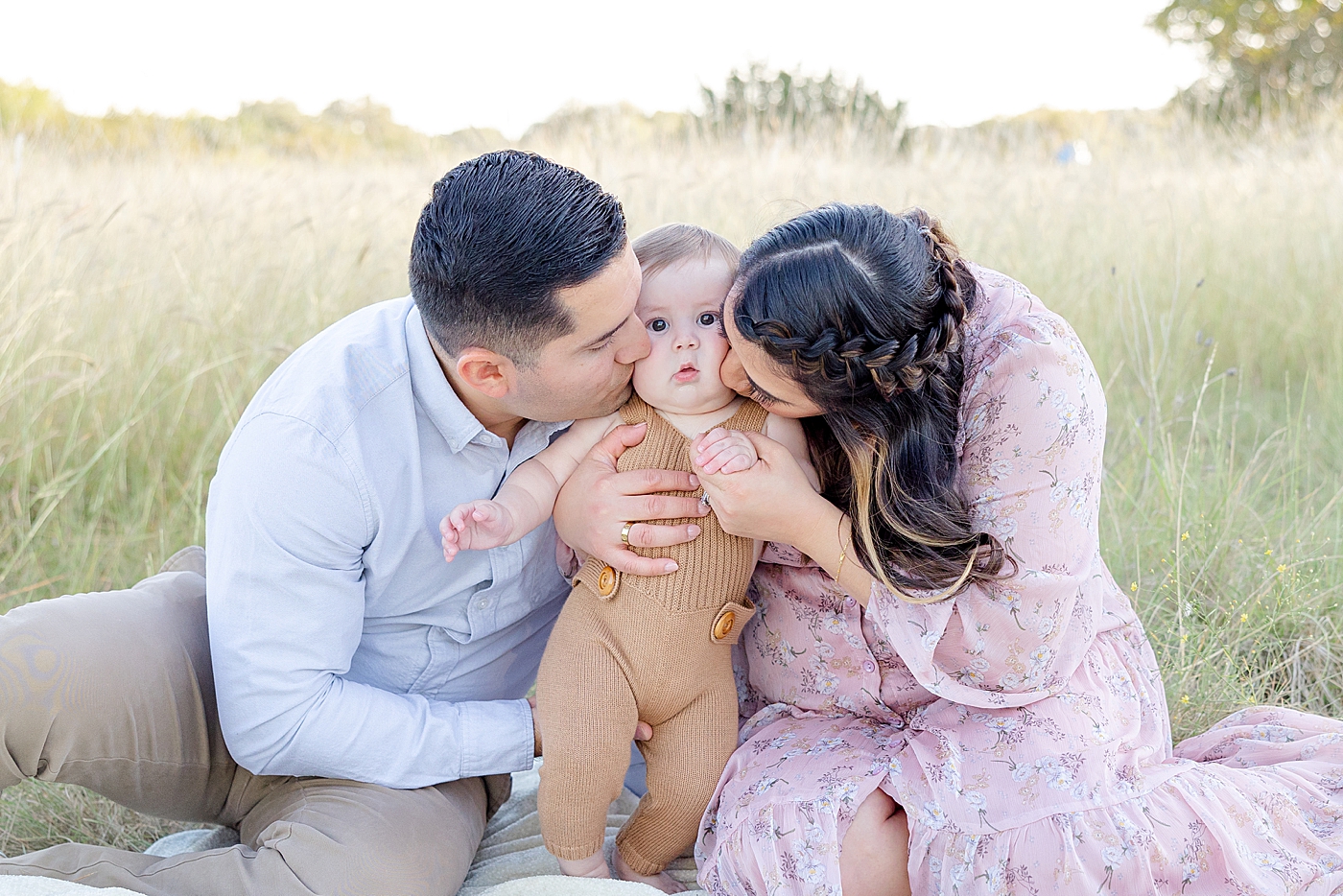 Mom and dad kissing their baby boy's cheeks during Six Month Milestone Session | Image by Sana Ahmed Photography