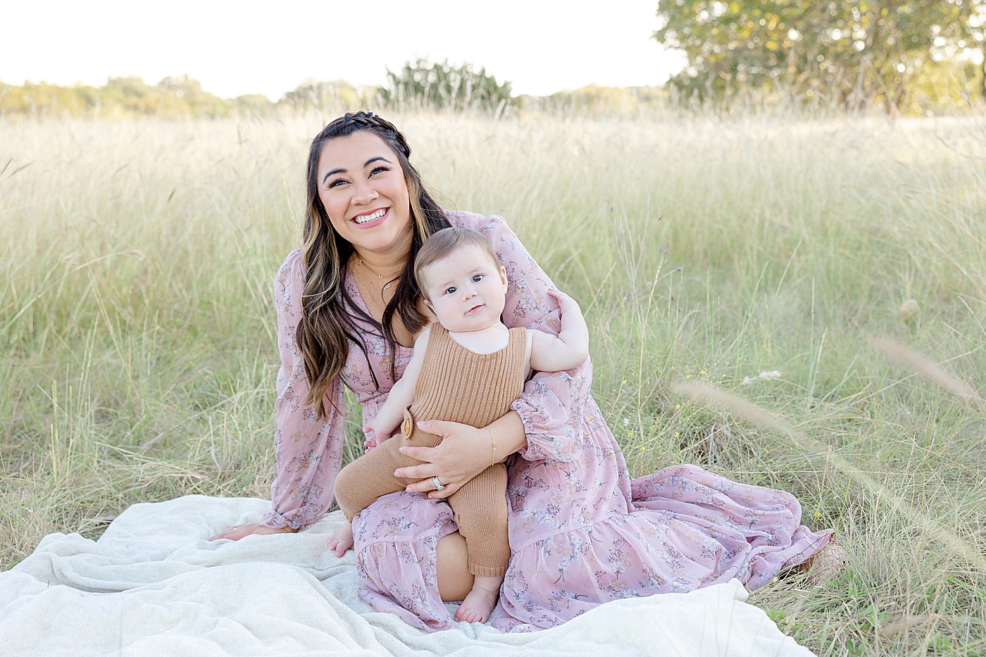 Mom in pink dress sitting in the grass with her baby boy | Image by Sana Ahmed Photography