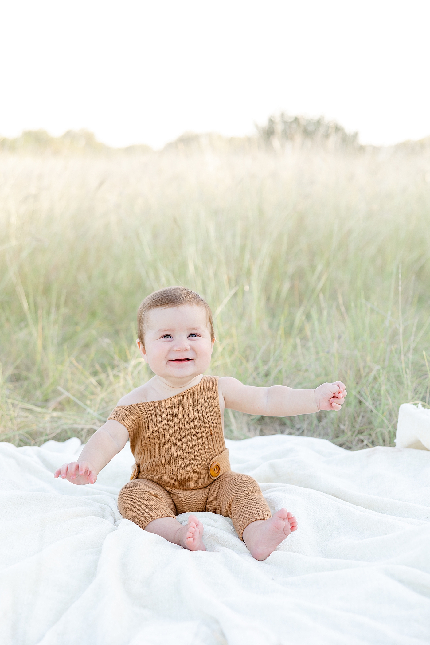 Smiling baby boy sitting in the grass during Six Month Milestone Session | Image by Sana Ahmed Photography