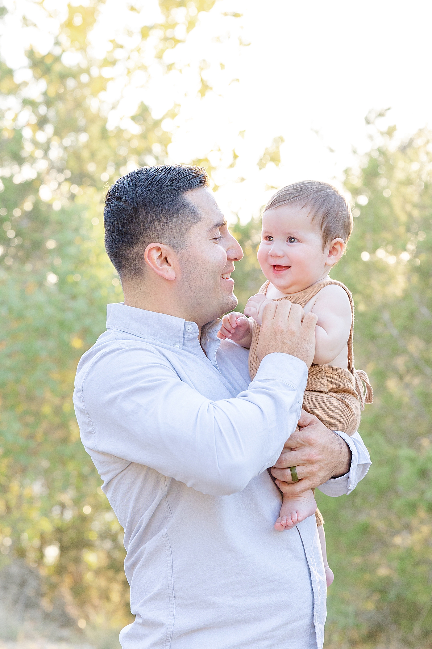 Dad laughing and holding her baby boy during Six Month Milestone Session | Image by Sana Ahmed Photography
