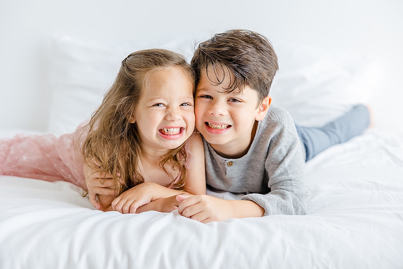 Toddle brother and sister laying on a white bed | Studio Family Sessions Austin with Sana Ahmed Photography