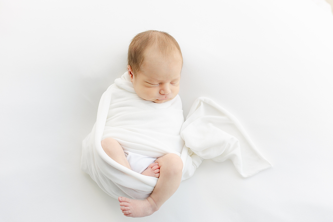 Sleeping newborn baby boy wrapped in a white swaddle | Image by Sana Ahmed Photography 