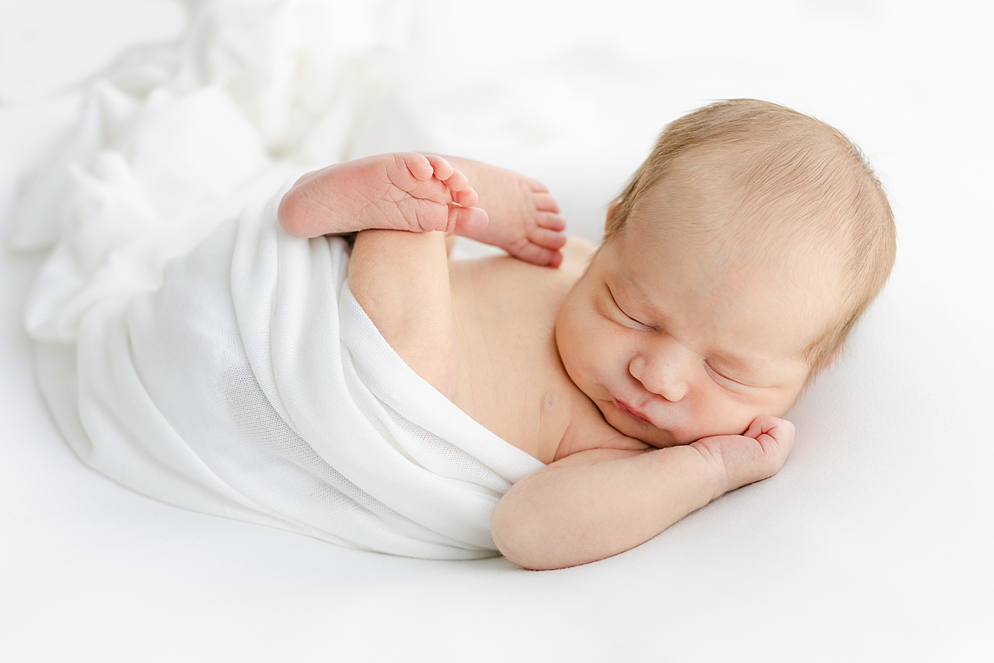 Detail of sleeping newborn baby in a white swaddle | Image by Sana Ahmed Photography 
