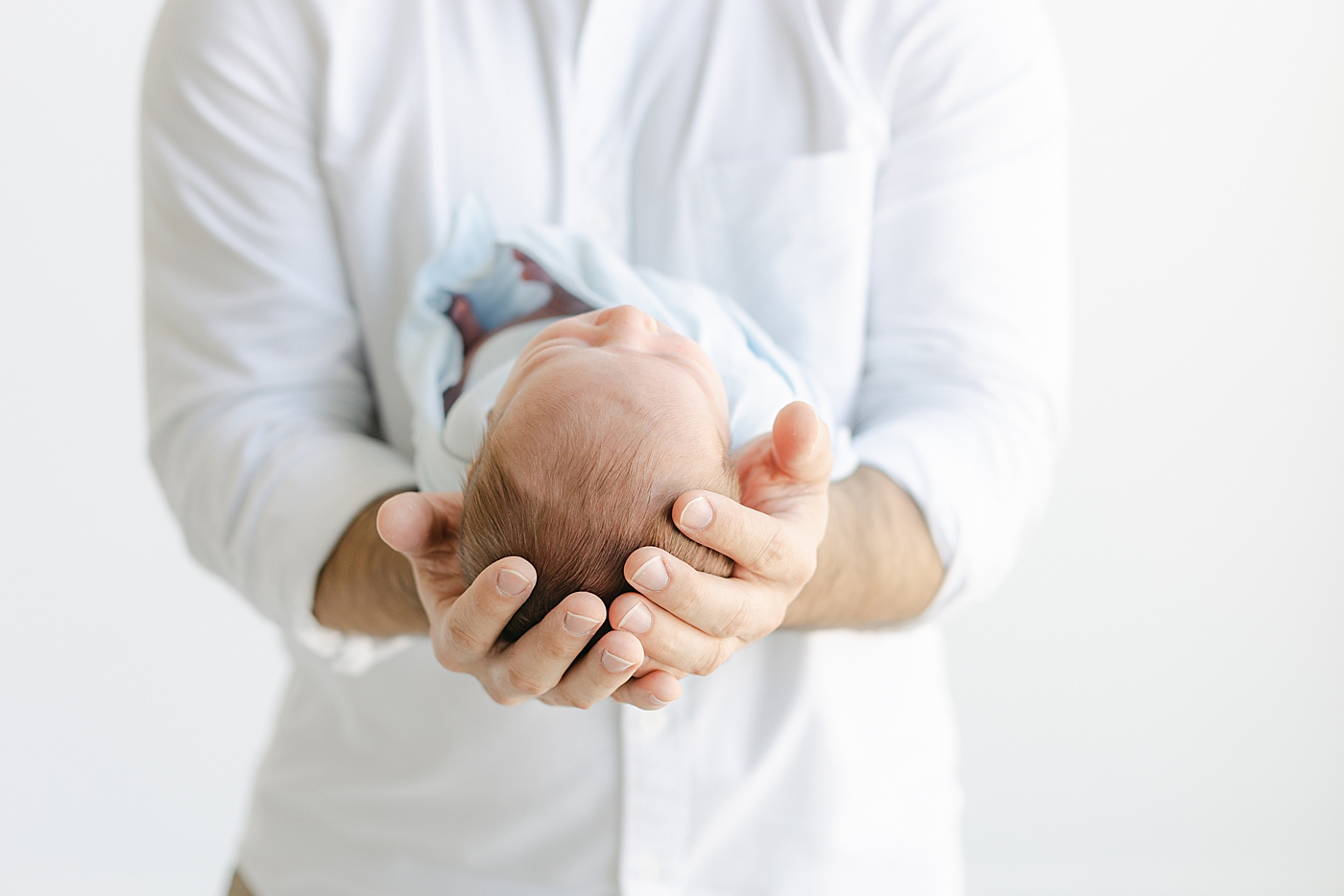 Detail of dad's hands while he holds his newborn baby | Image by Sana Ahmed Photography 