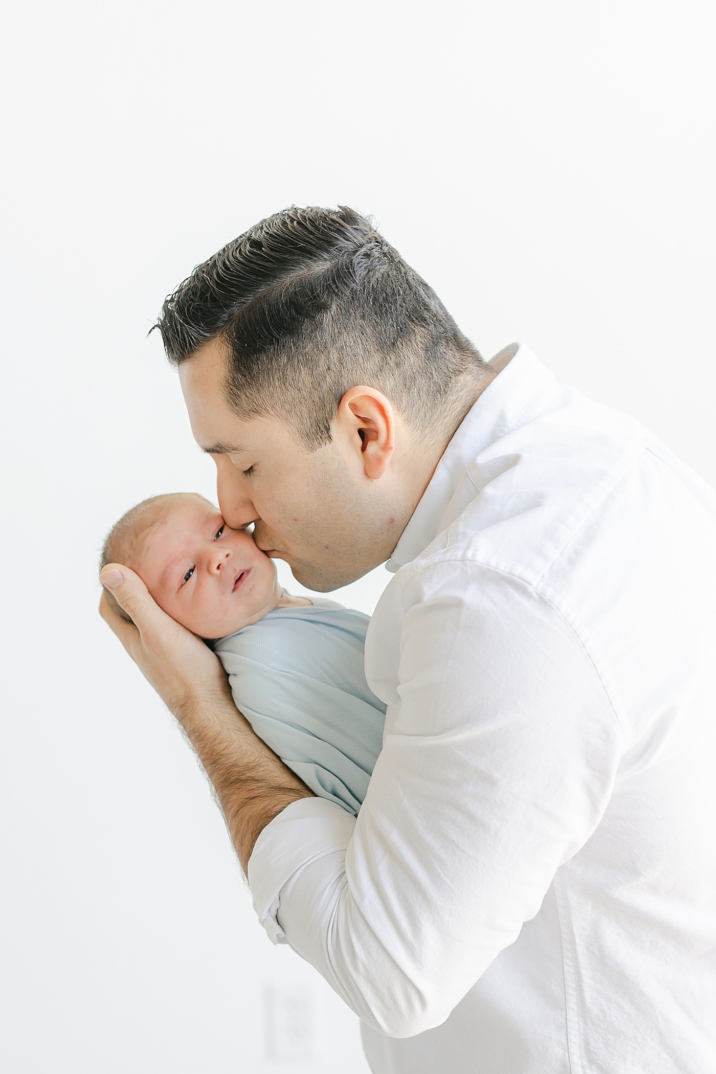 Dad kissing his new baby in the studio | Image by Sana Ahmed Photography 